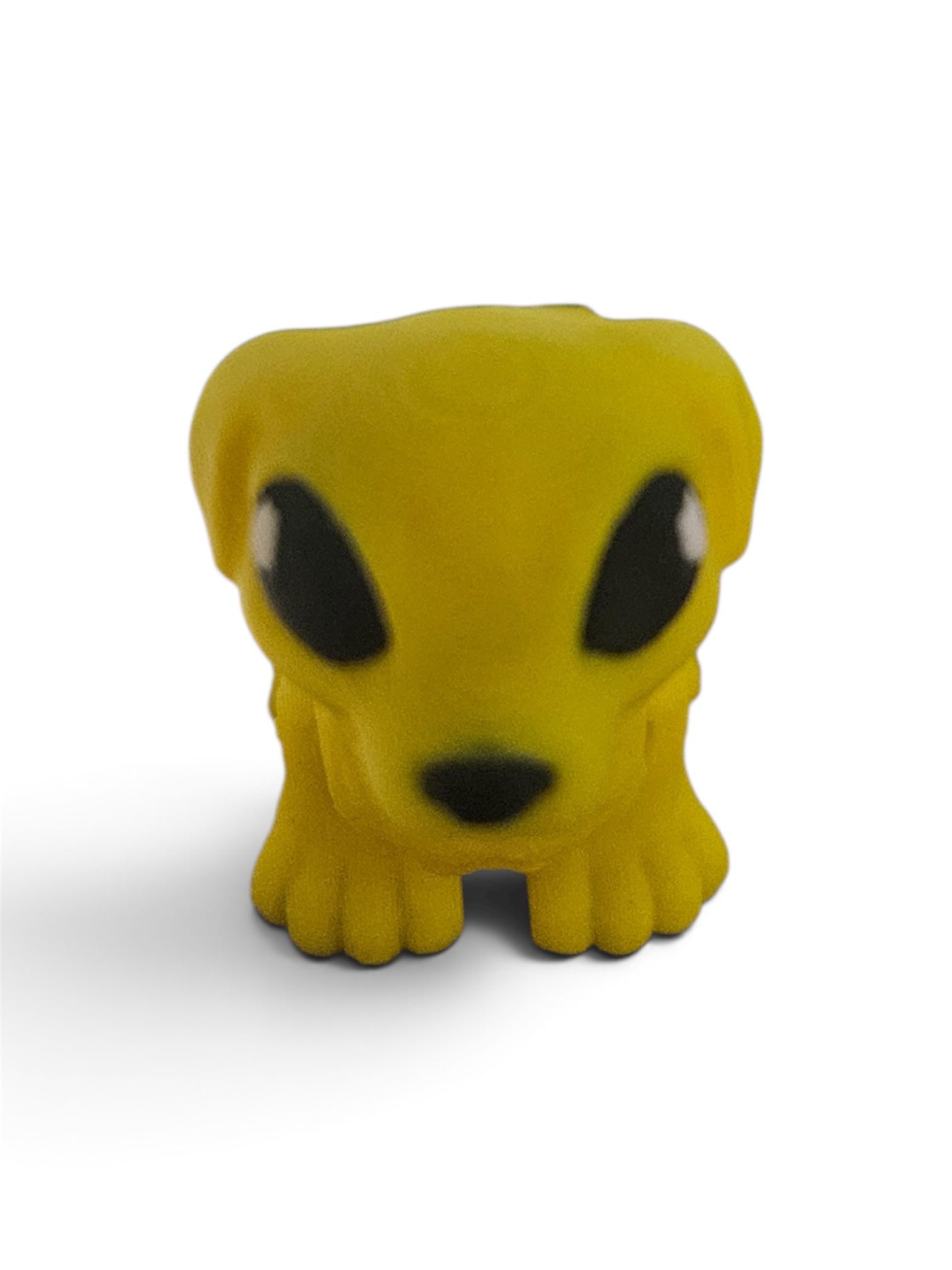 Yellow toy creature with black eyes and paws on a white background