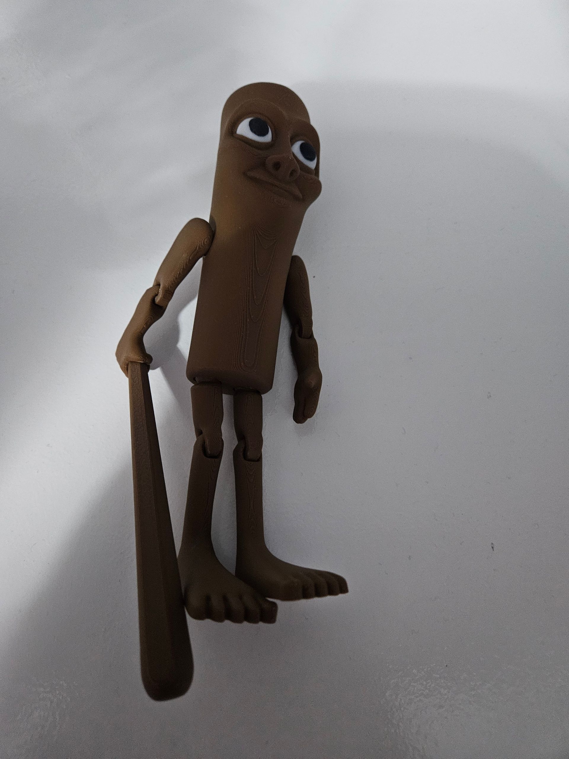 A brown figure with a club and an odd expression, standing against a white backdrop.
