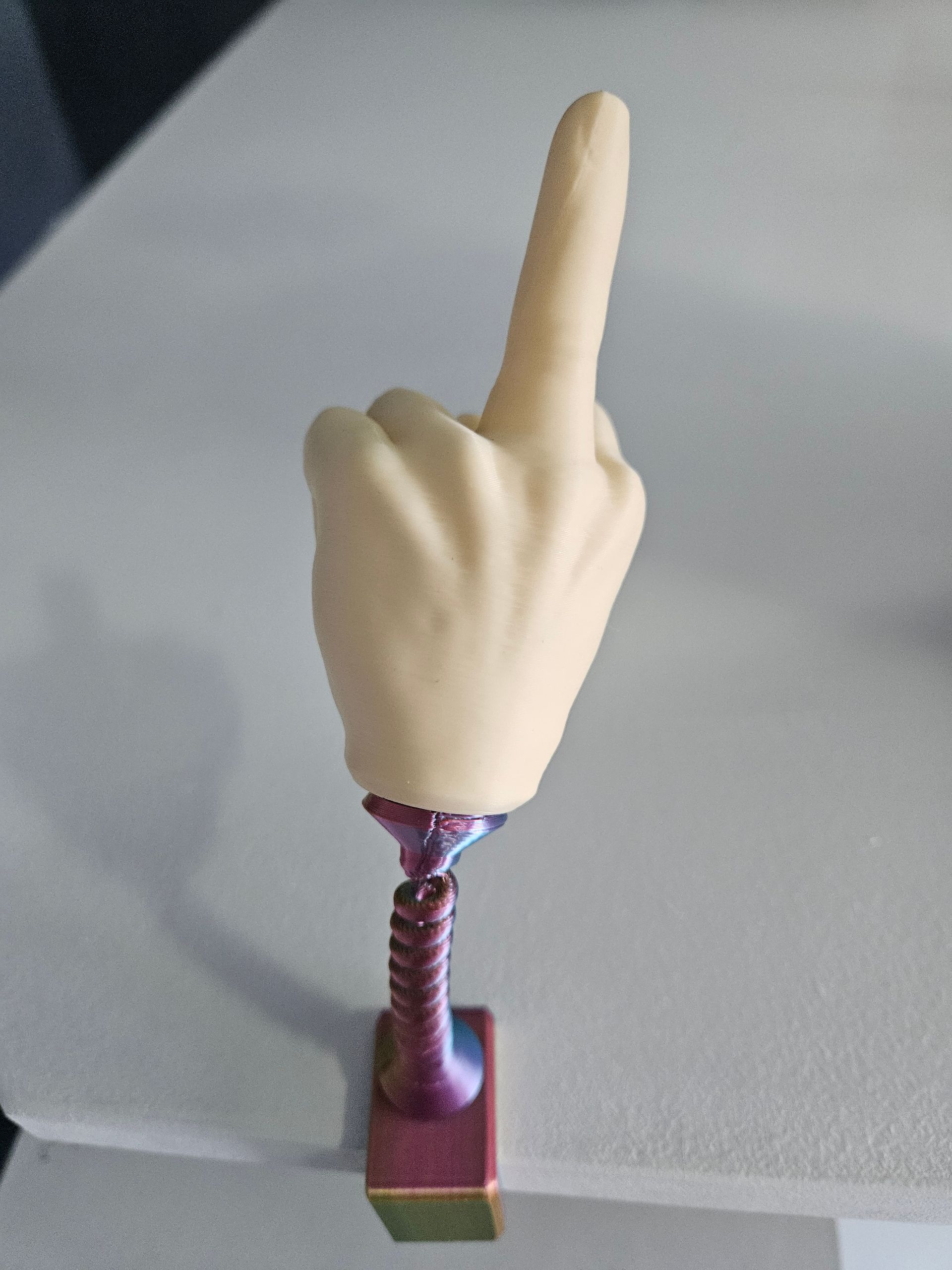 A hand with an extended index finger, atop a purple spring and base.