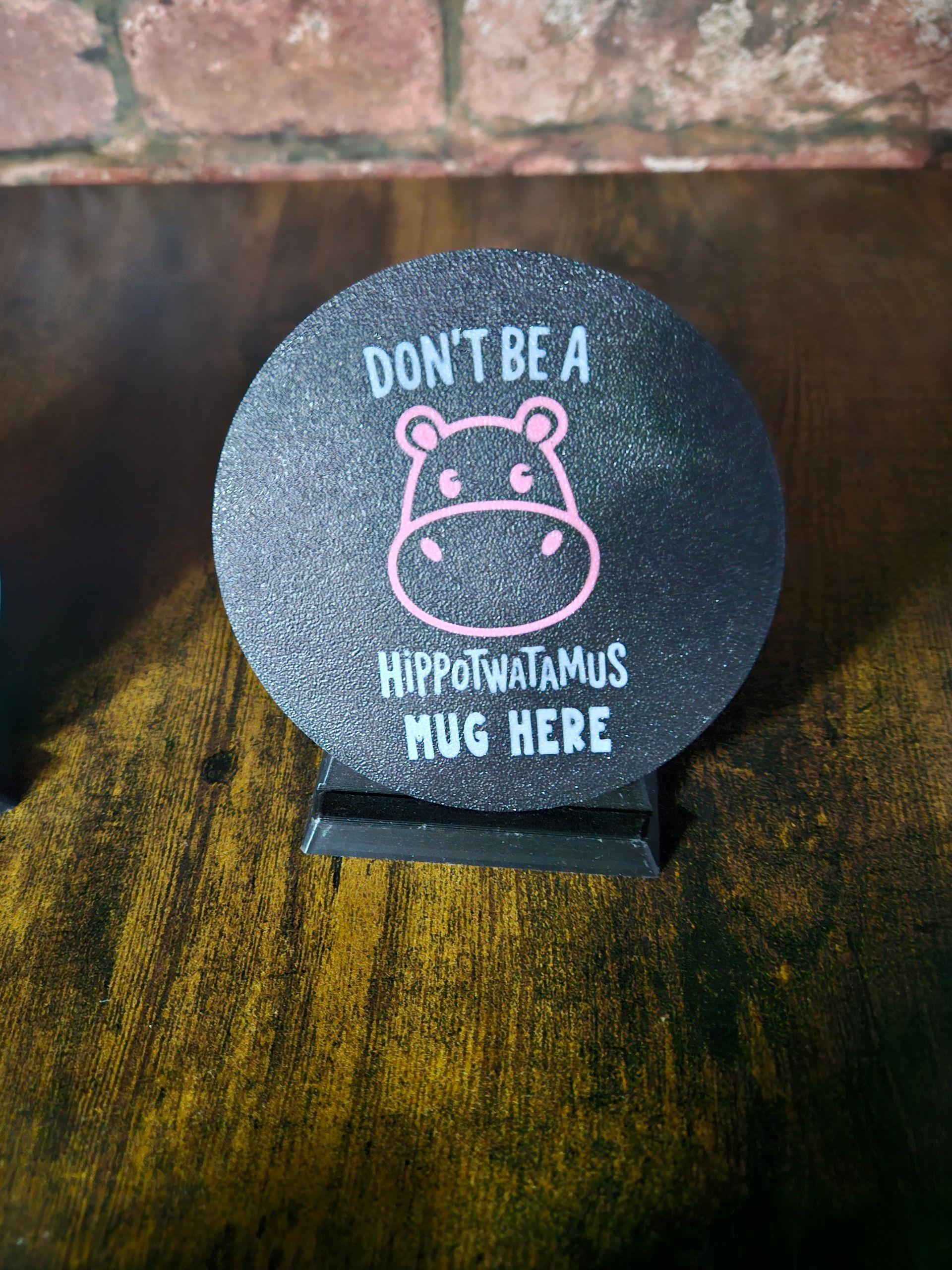 Black coaster with a hippo graphic and text