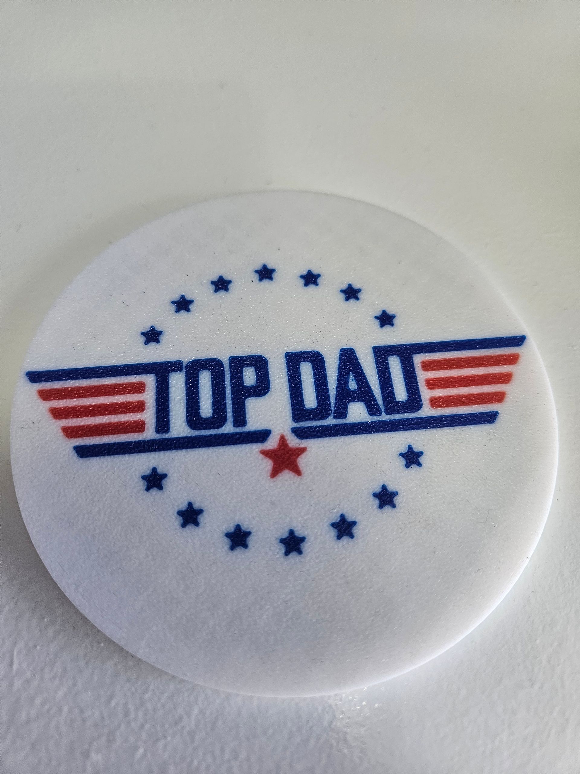 White button with blue and red “TOP DAY” logo and stars in a circular pattern
