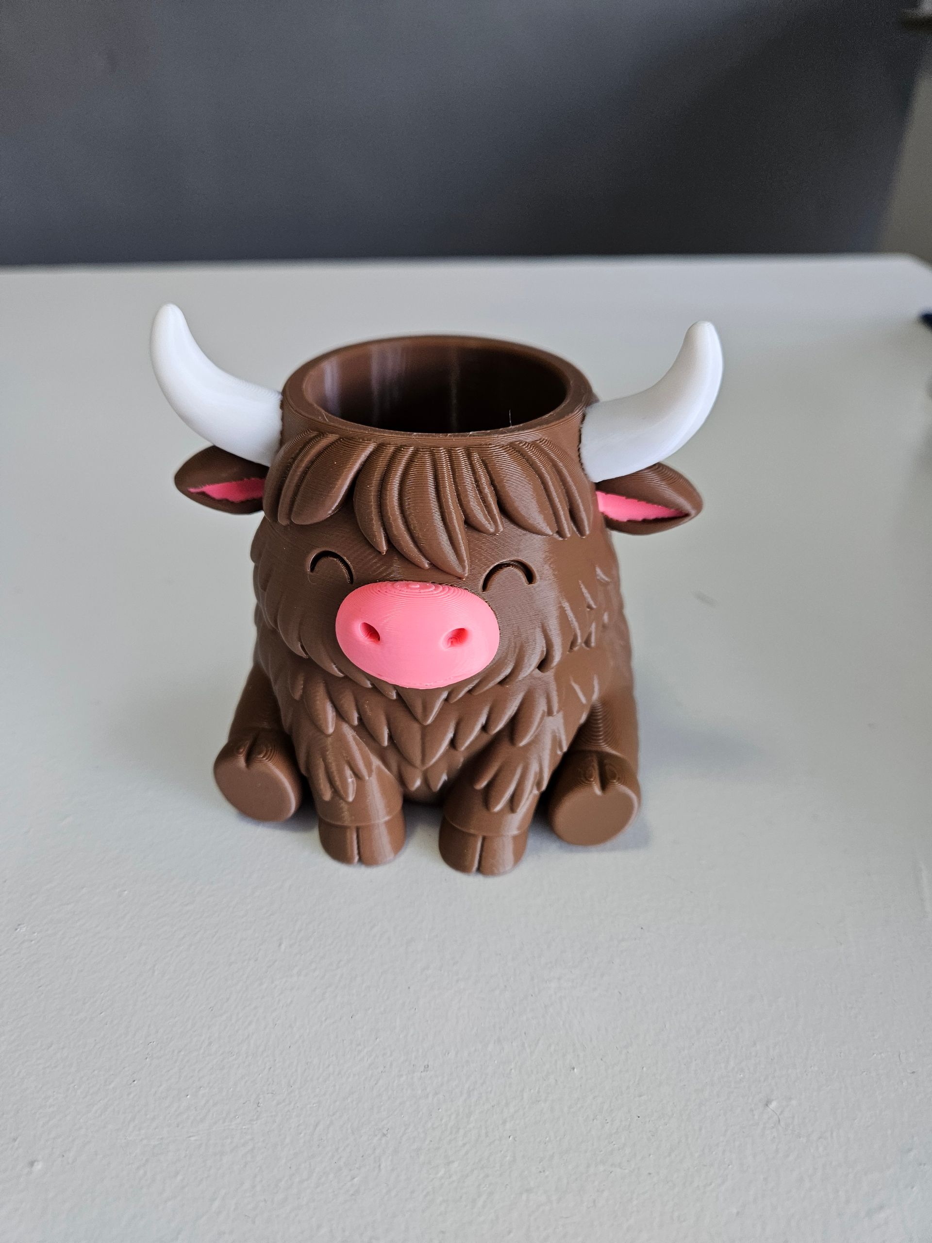 Brown yak-shaped pen holder with pink nose and inner ears, white horns, and a smiling face.