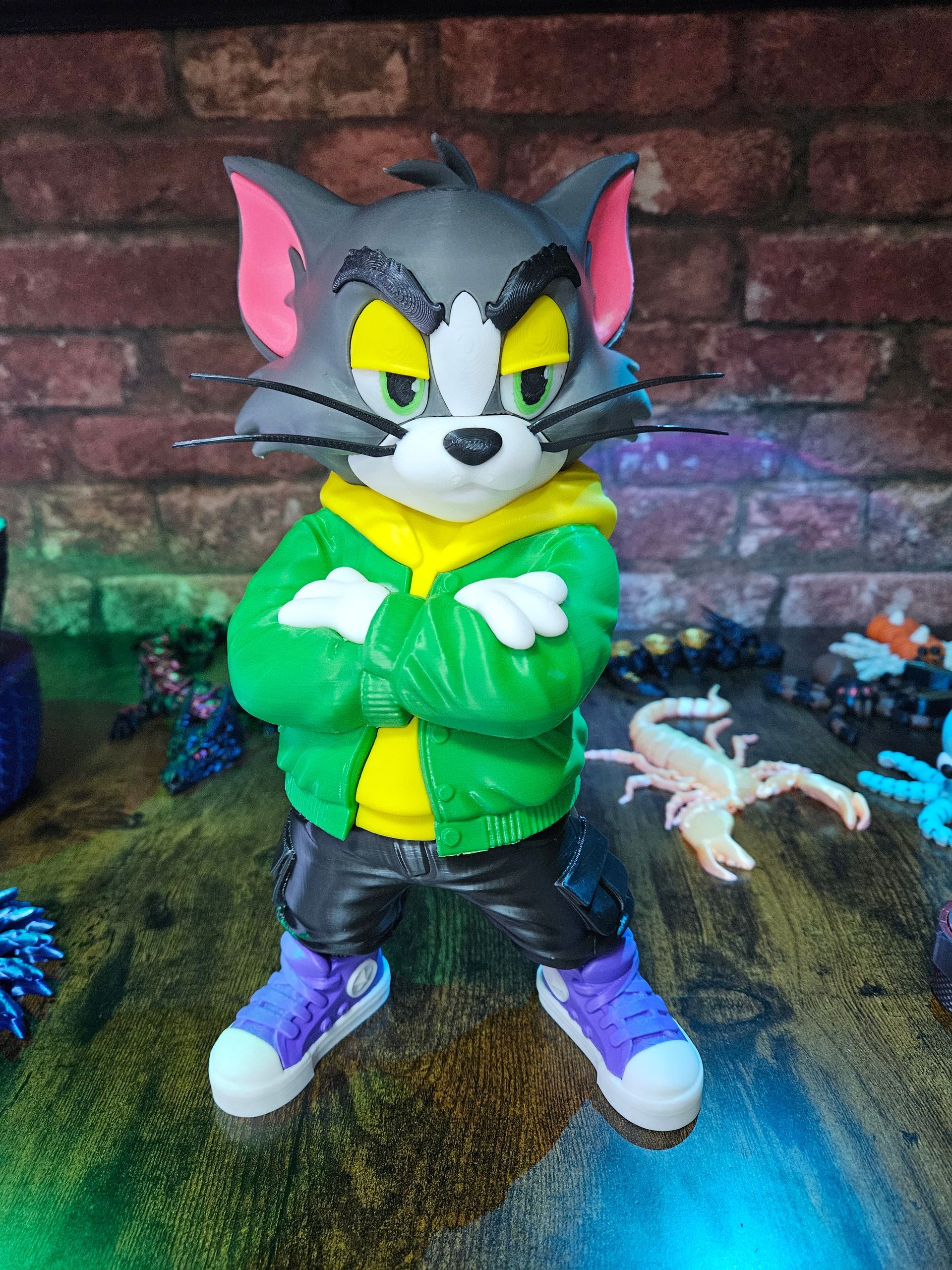 Tom cat figurine in a green jacket, black pants, and purple shoes, arms crossed.
