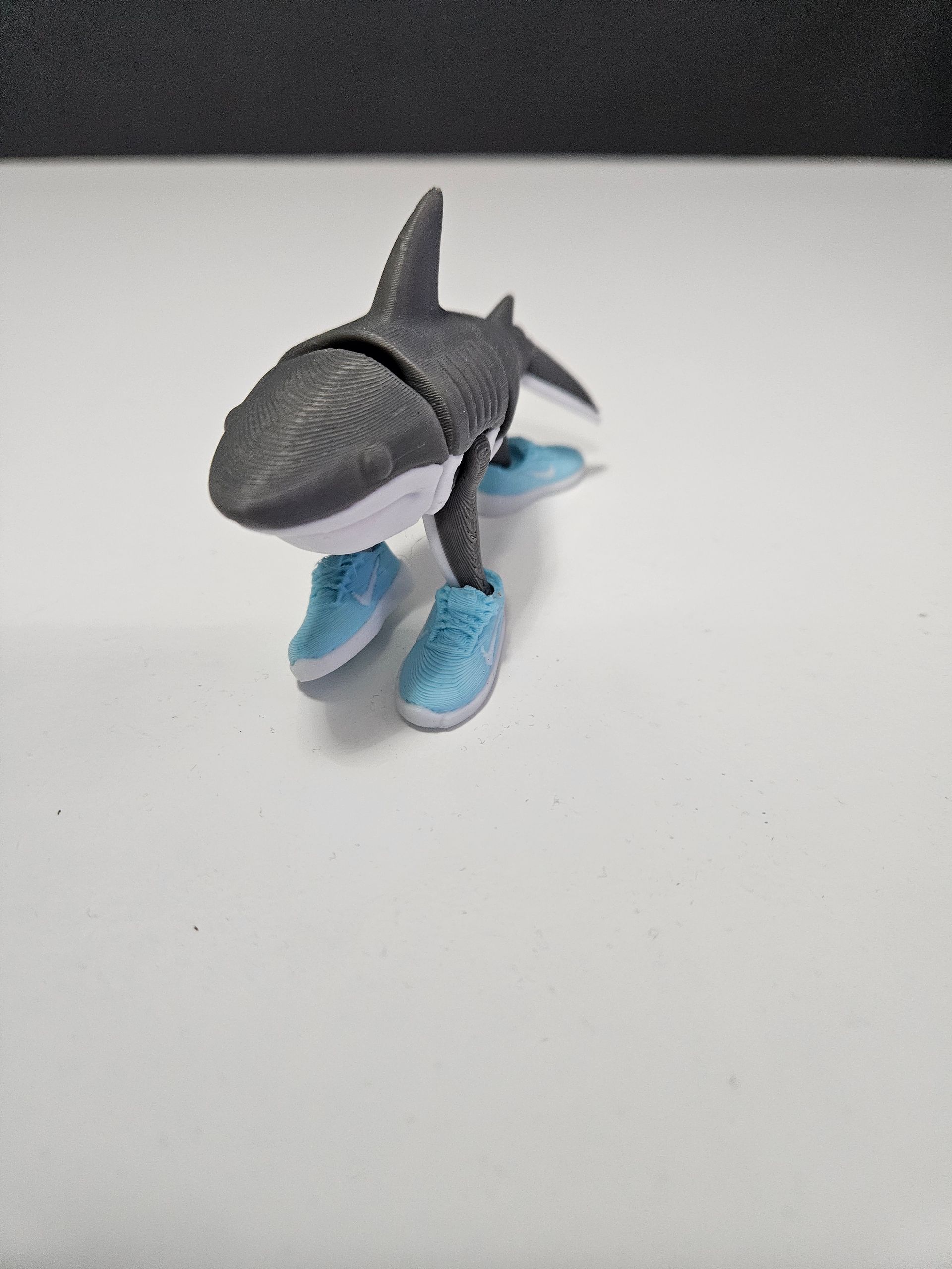 Toy shark wearing light blue sneakers.