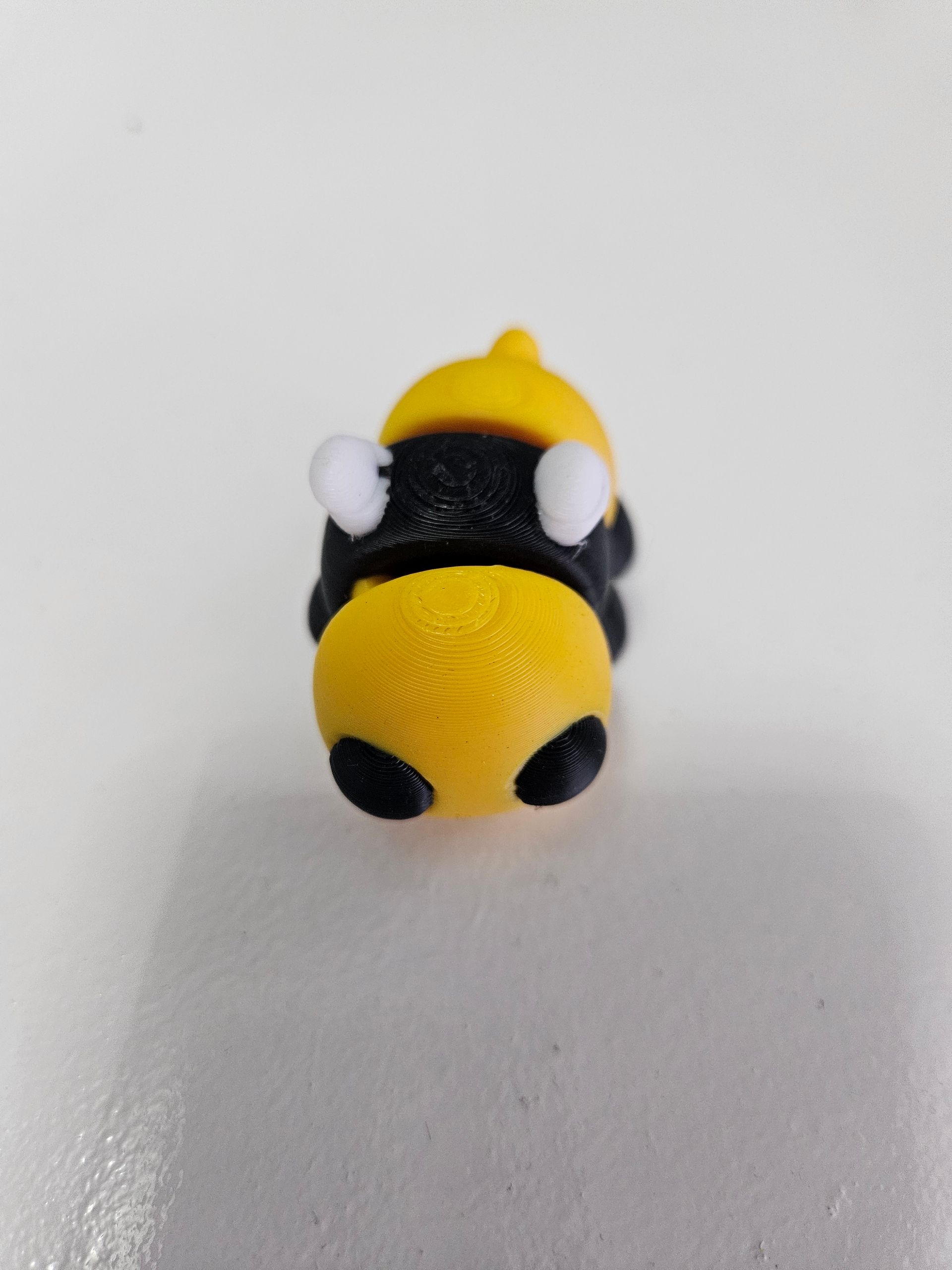 Yellow and black toy bumblebee on a white surface.