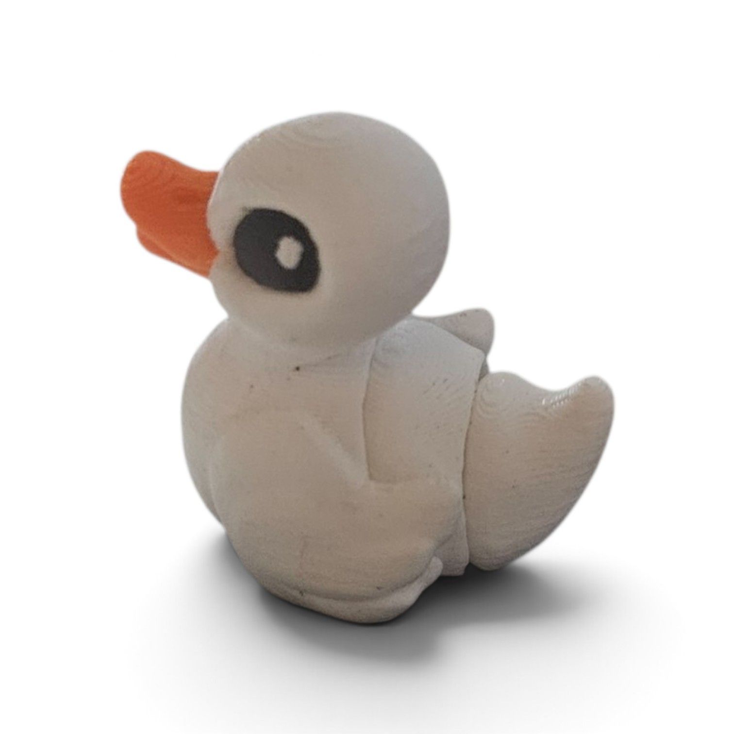 Small white duck figurine with orange beak and black eye, sitting on a white background