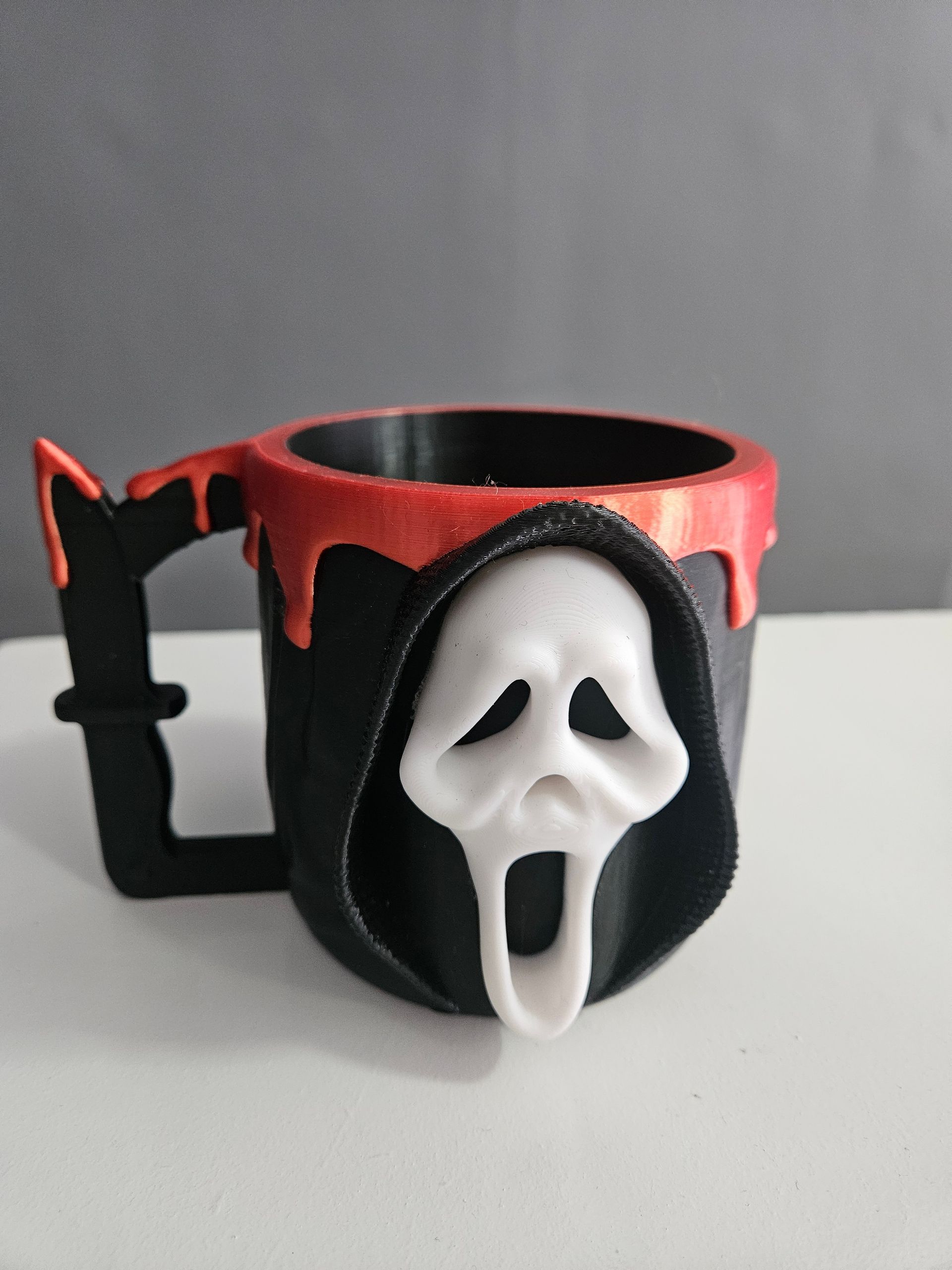 Black Scream mask-themed mug with red drips and a knife-shaped handle.