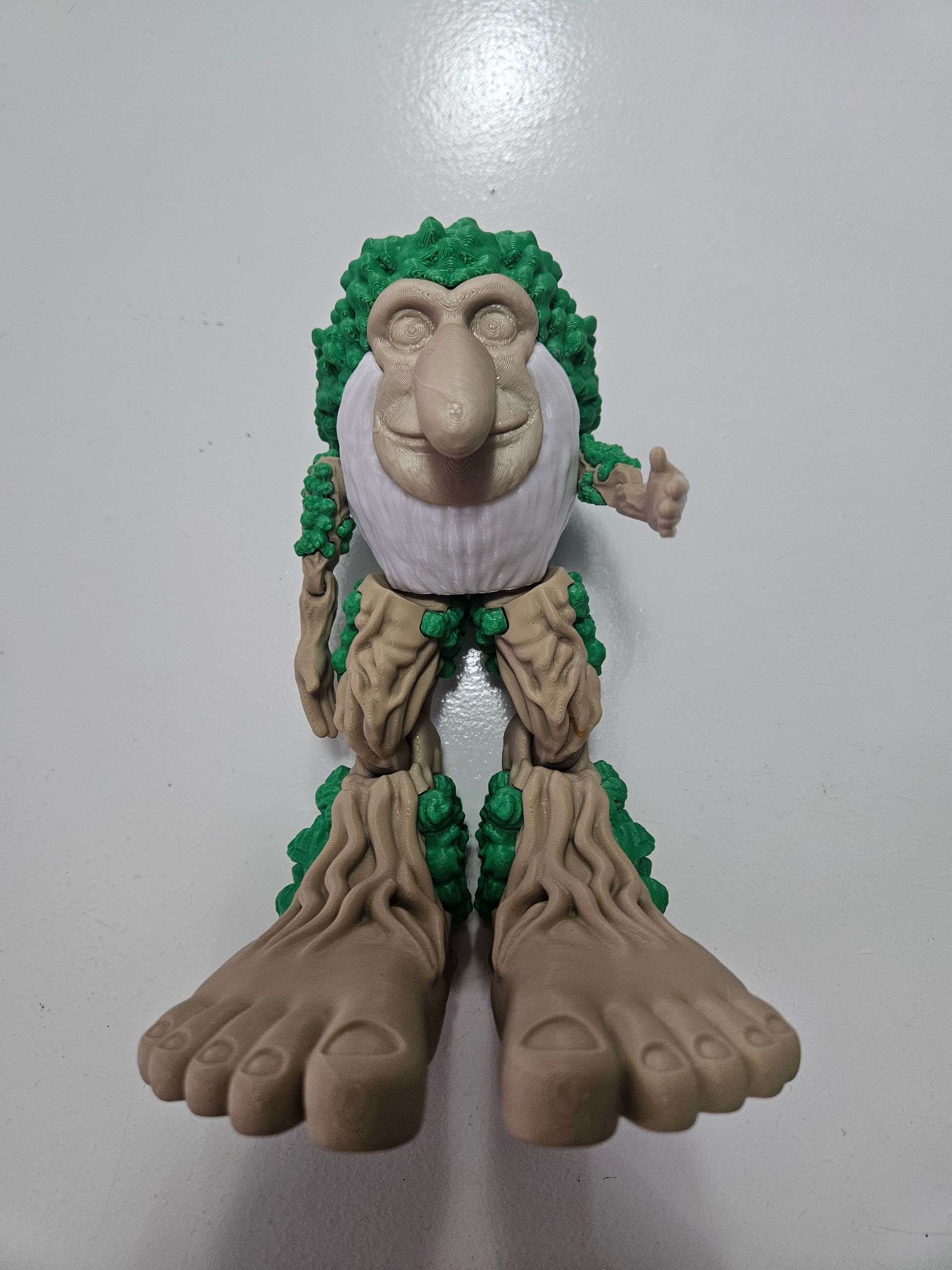 Toy figure of a green-haired creature with tree-like legs and feet, and a large nose, standing.
