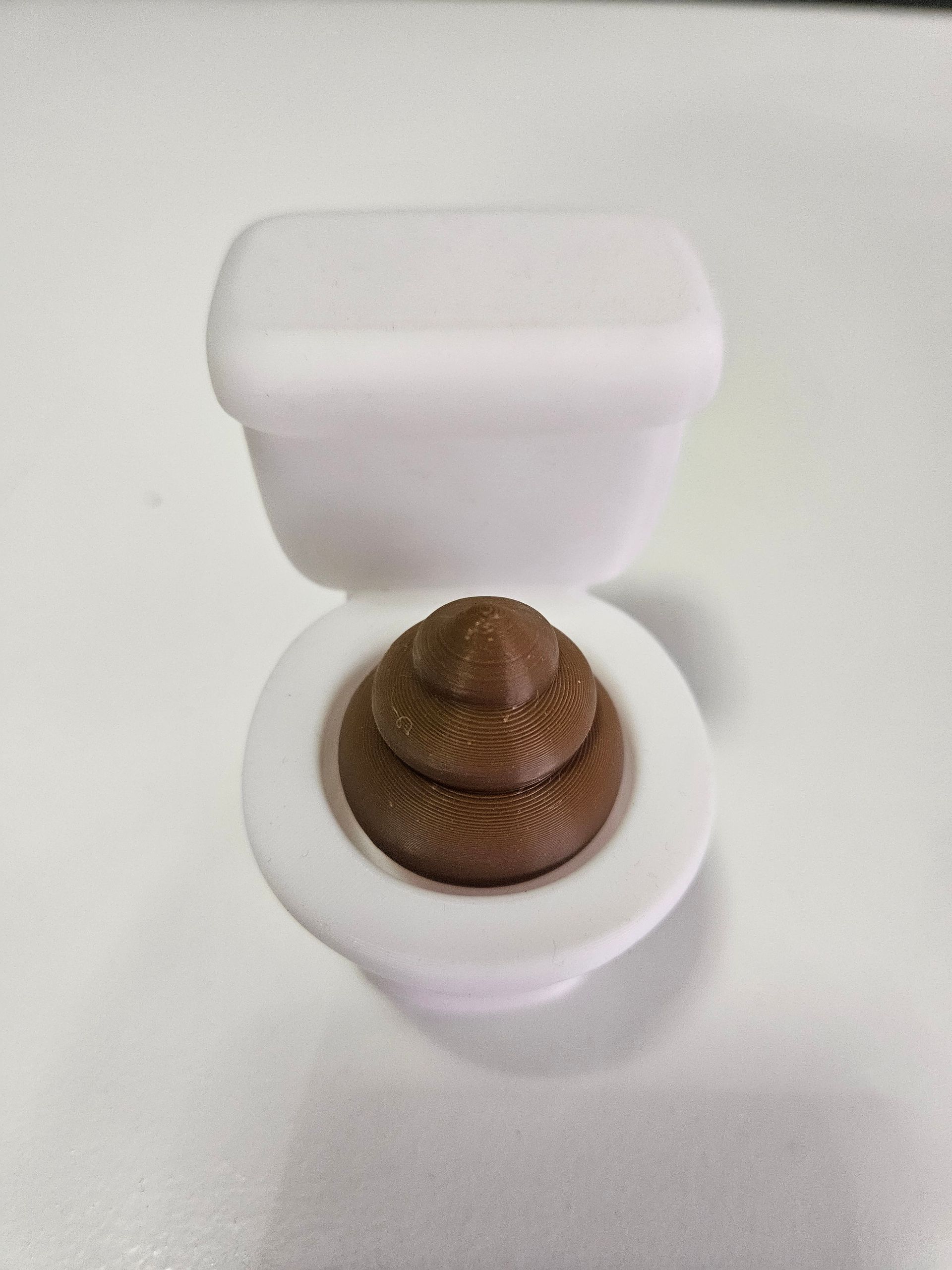 White toilet bowl with a brown poop emoji-like plush inside.