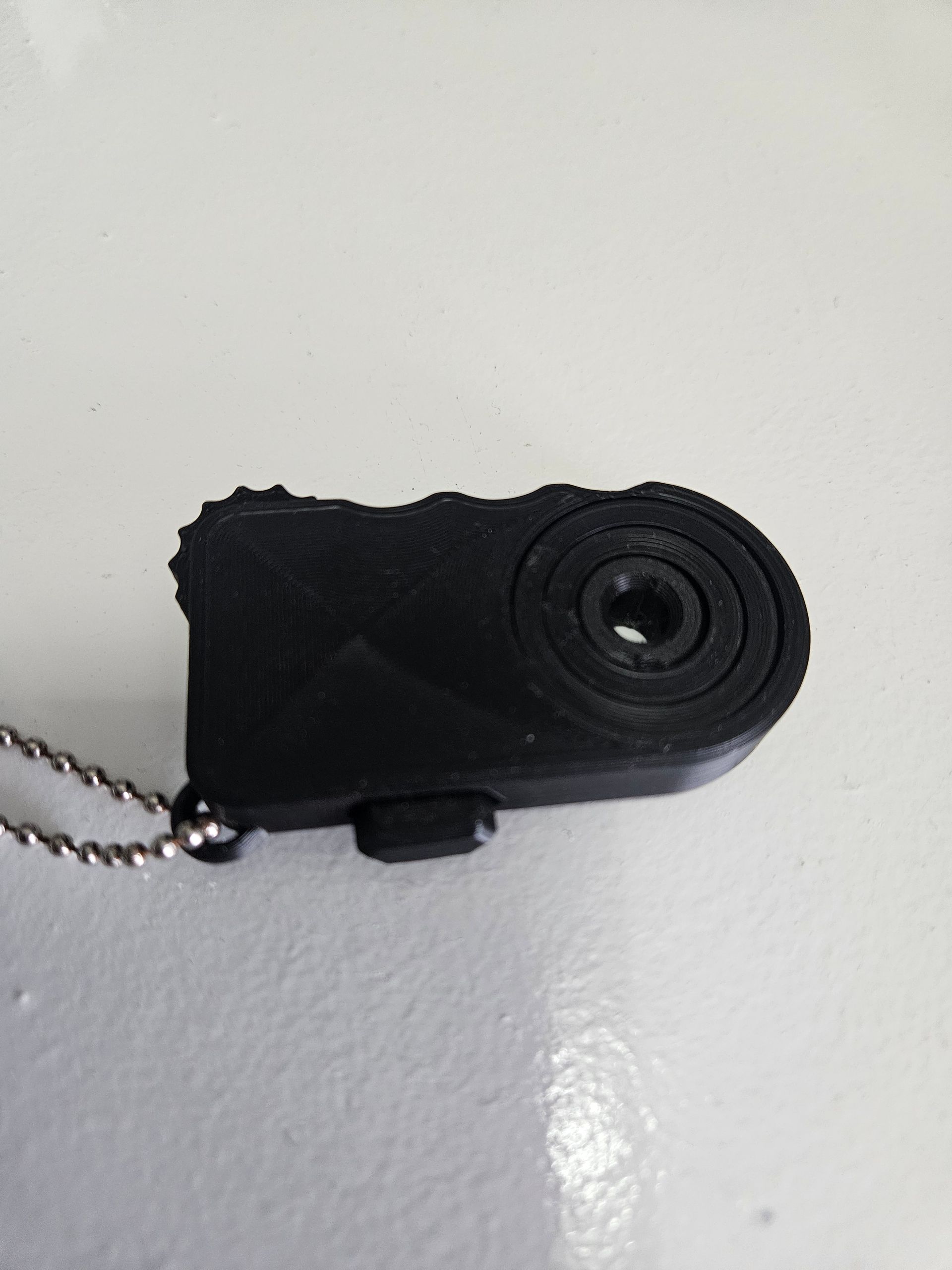 Black handheld mini flashlight keychain on a white surface