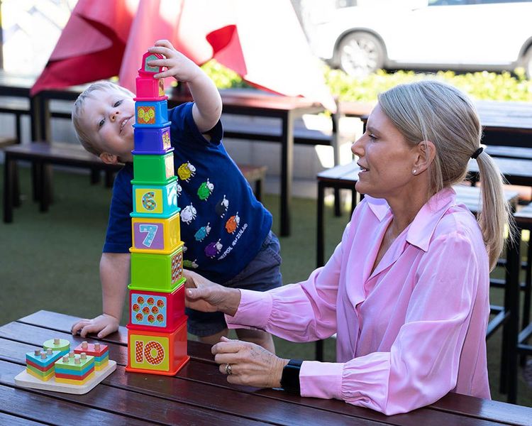A woman and a child are playing a game at a table.