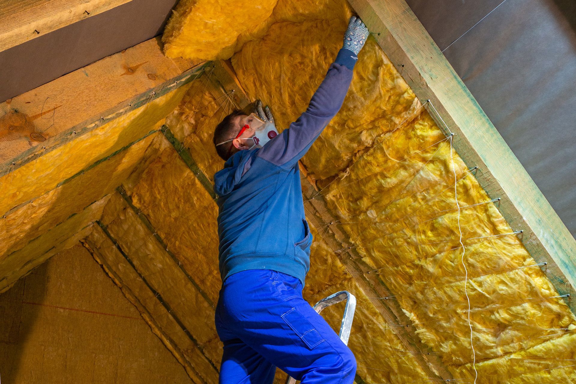 A man is insulating the attic of a house. A man is insulating the attic of a house.