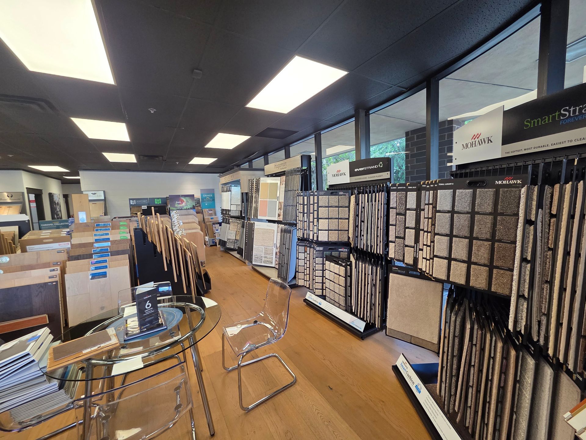 Carpet store aisle with sample racks, display tables, and overhead fluorescent lights