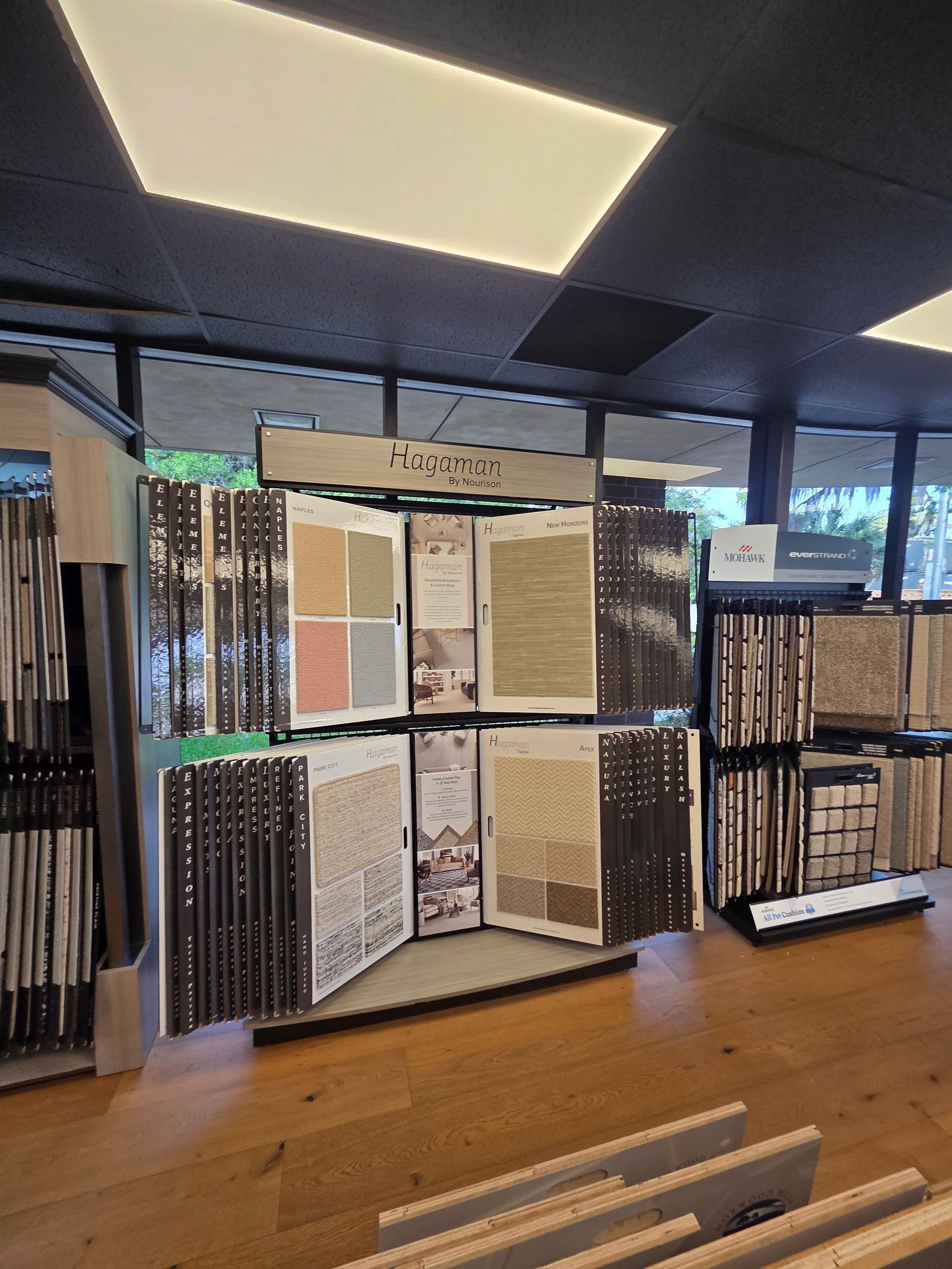 Carpet and flooring sample displays in a showroom with overhead lights and wood floor.