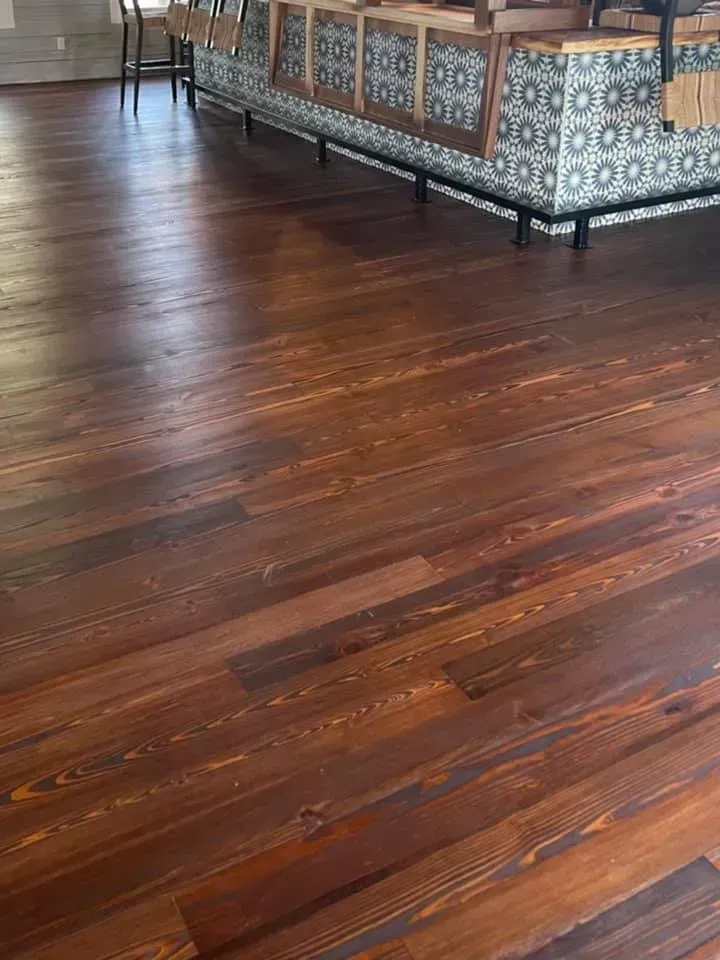 Wooden floor in a room with patterned upholstered benches along the wall.