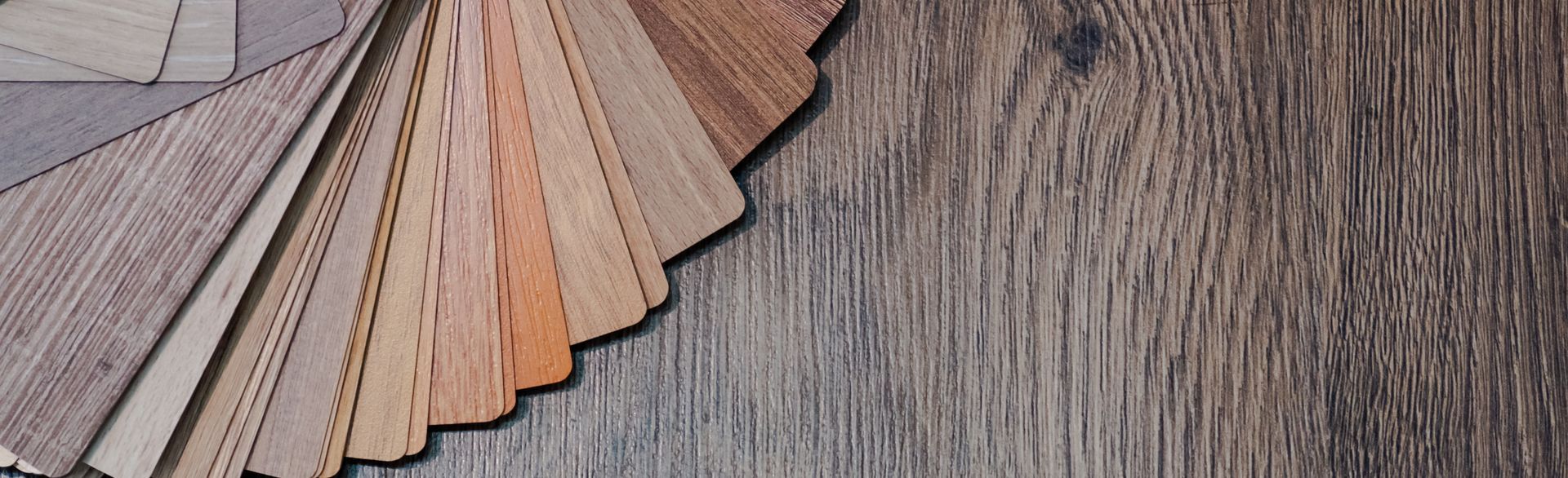 Fan of wood flooring samples on a gray wooden surface