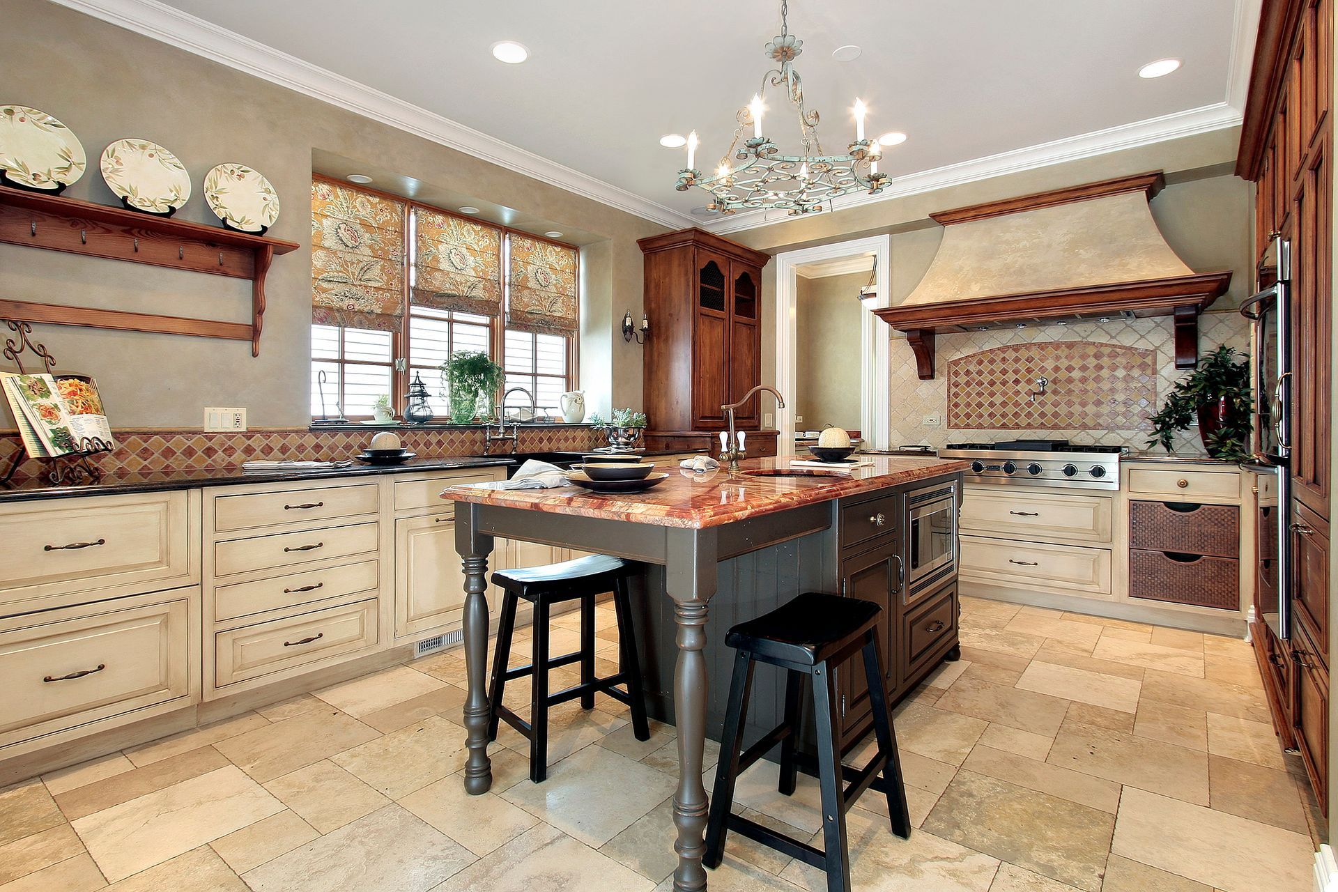 Spacious cream-toned kitchen with island, stools, chandelier, and decorative cabinetry