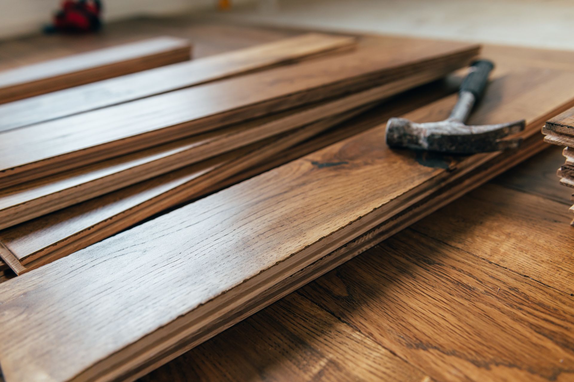 Hammer on wooden floorboards with stacked planks in a workshop