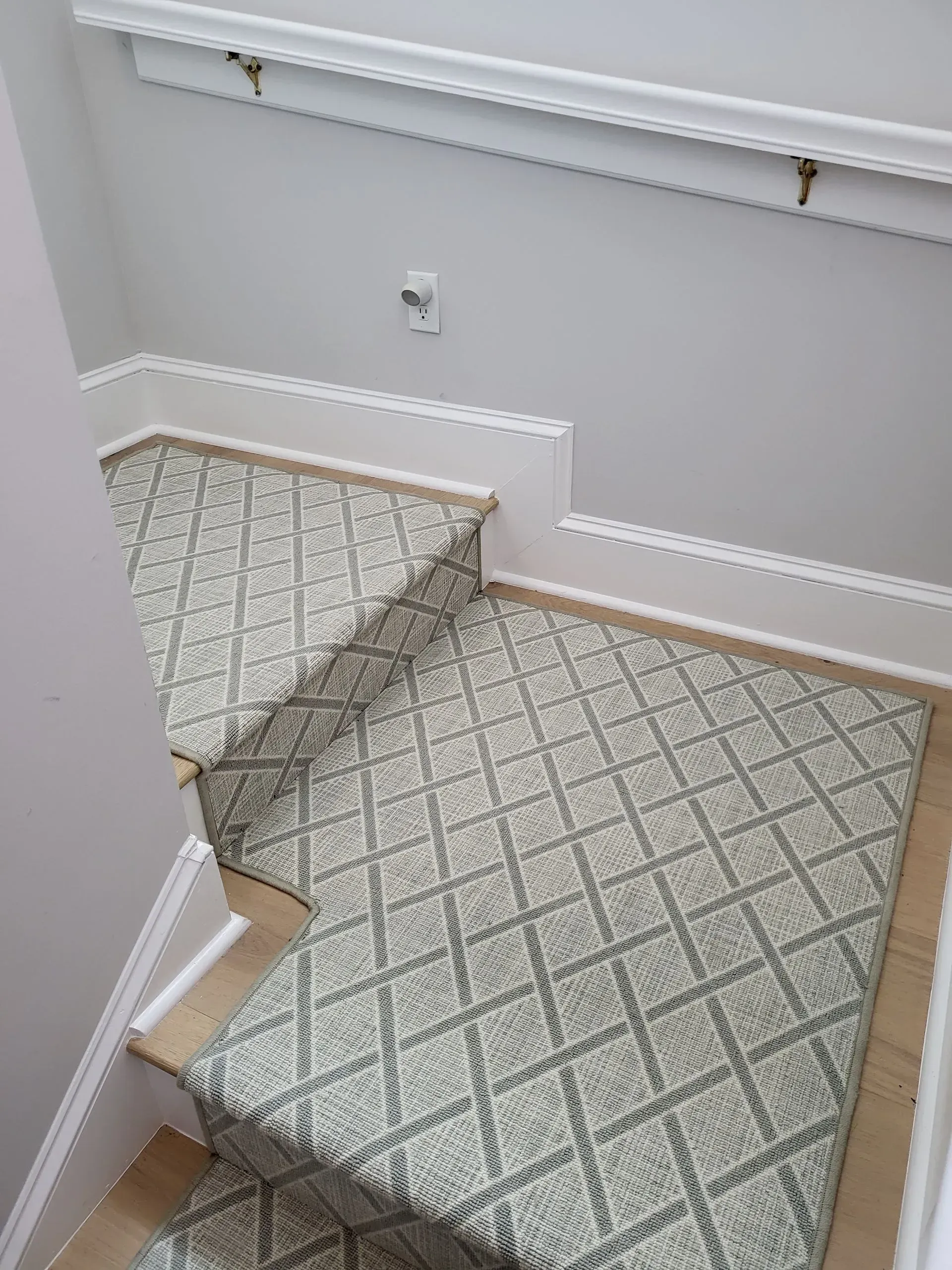 Carpeted staircase landing with white walls, railing, and patterned beige carpet.