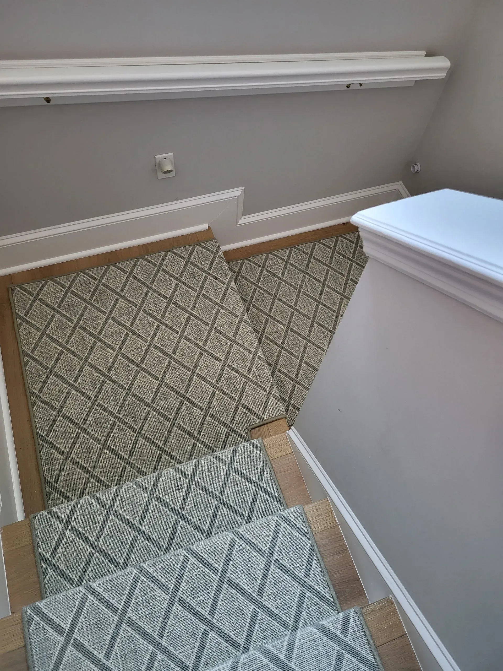 Carpeted staircase with patterned runner and white banister in a home interior.