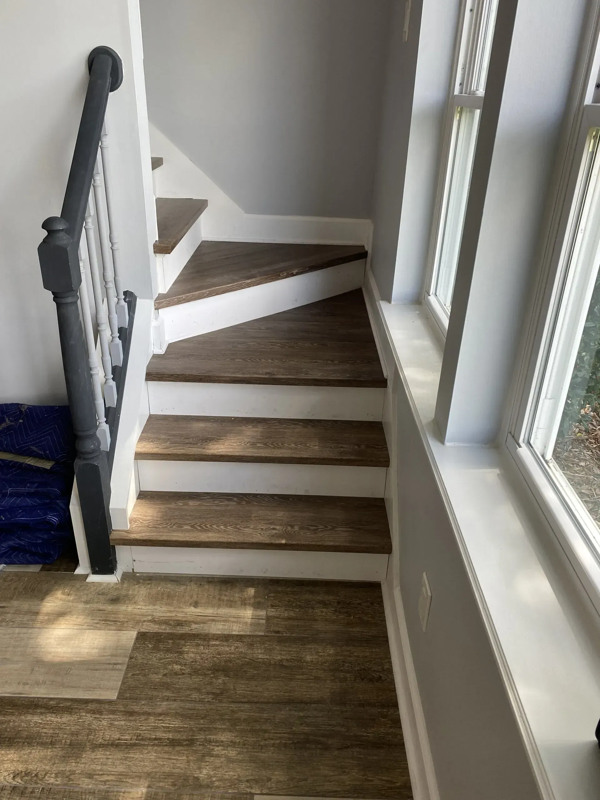 Indoor staircase with carpeted steps beside large windows and a white railing.