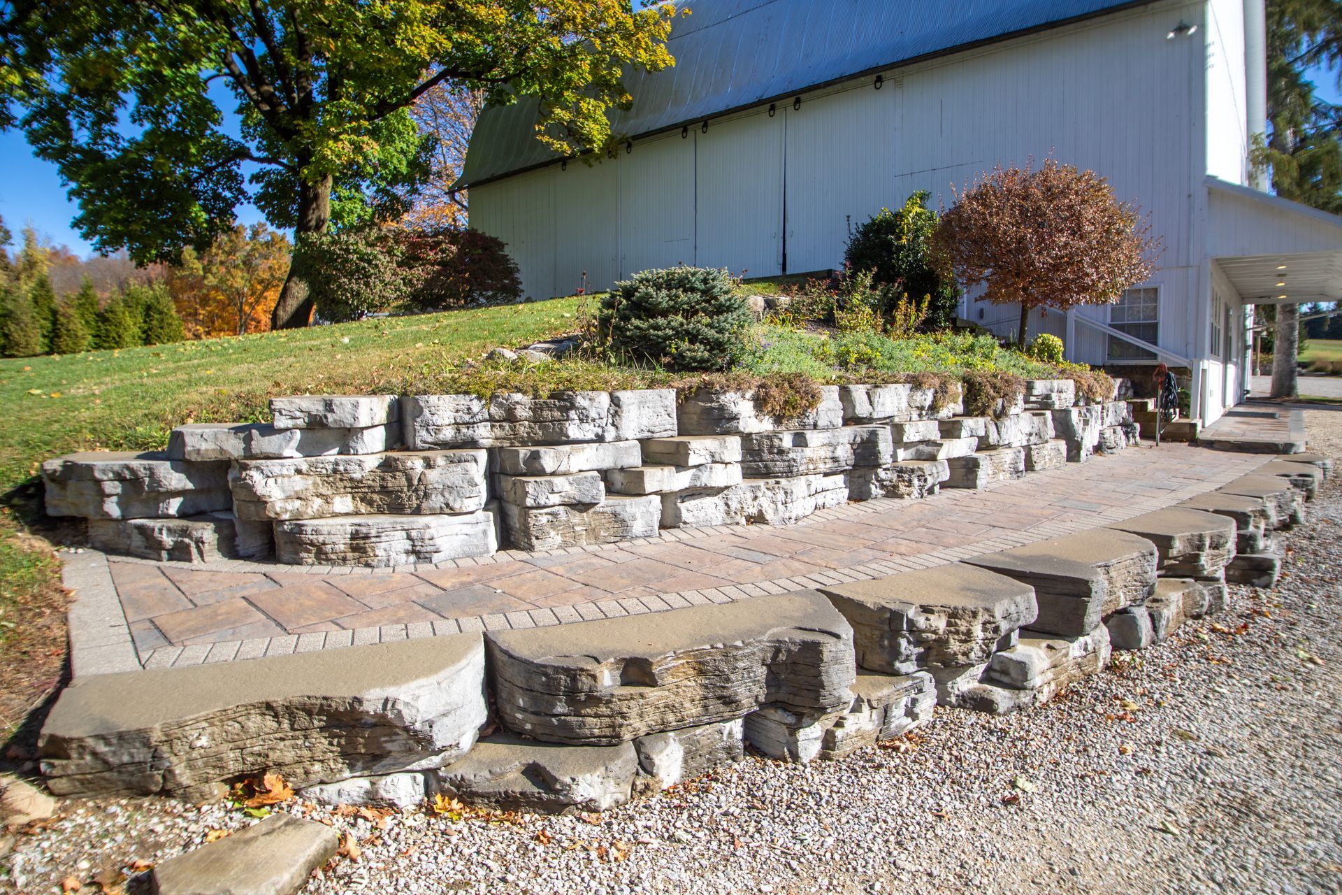 Stone retaining wall with steps and a brick pathway in front of a white building.