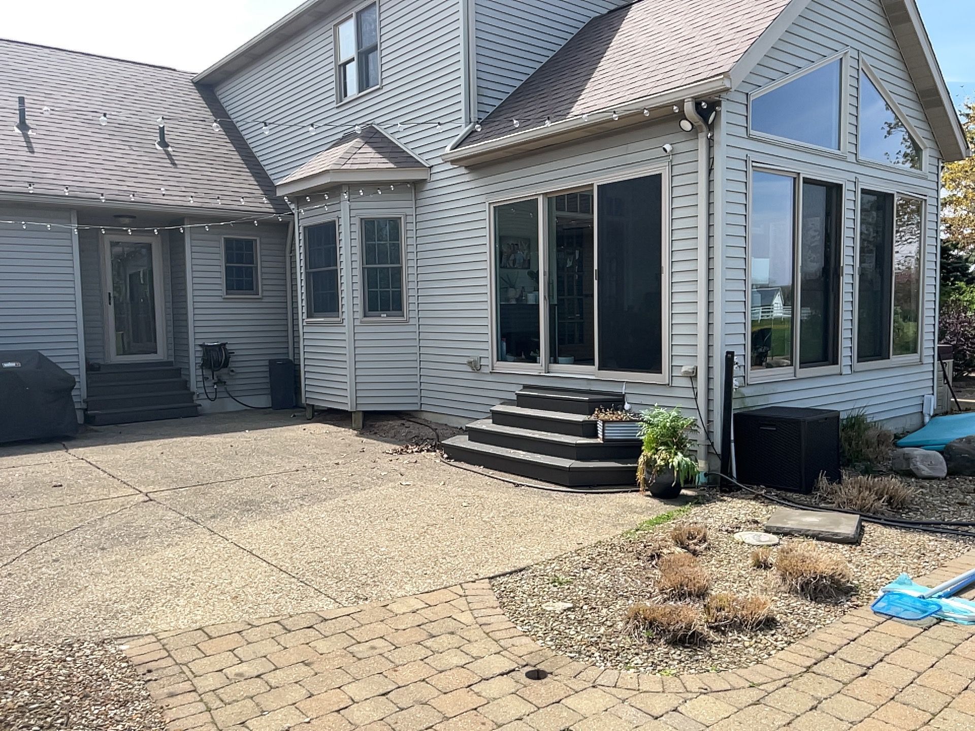 Backyard patio with light gray siding house, steps, and landscaping.