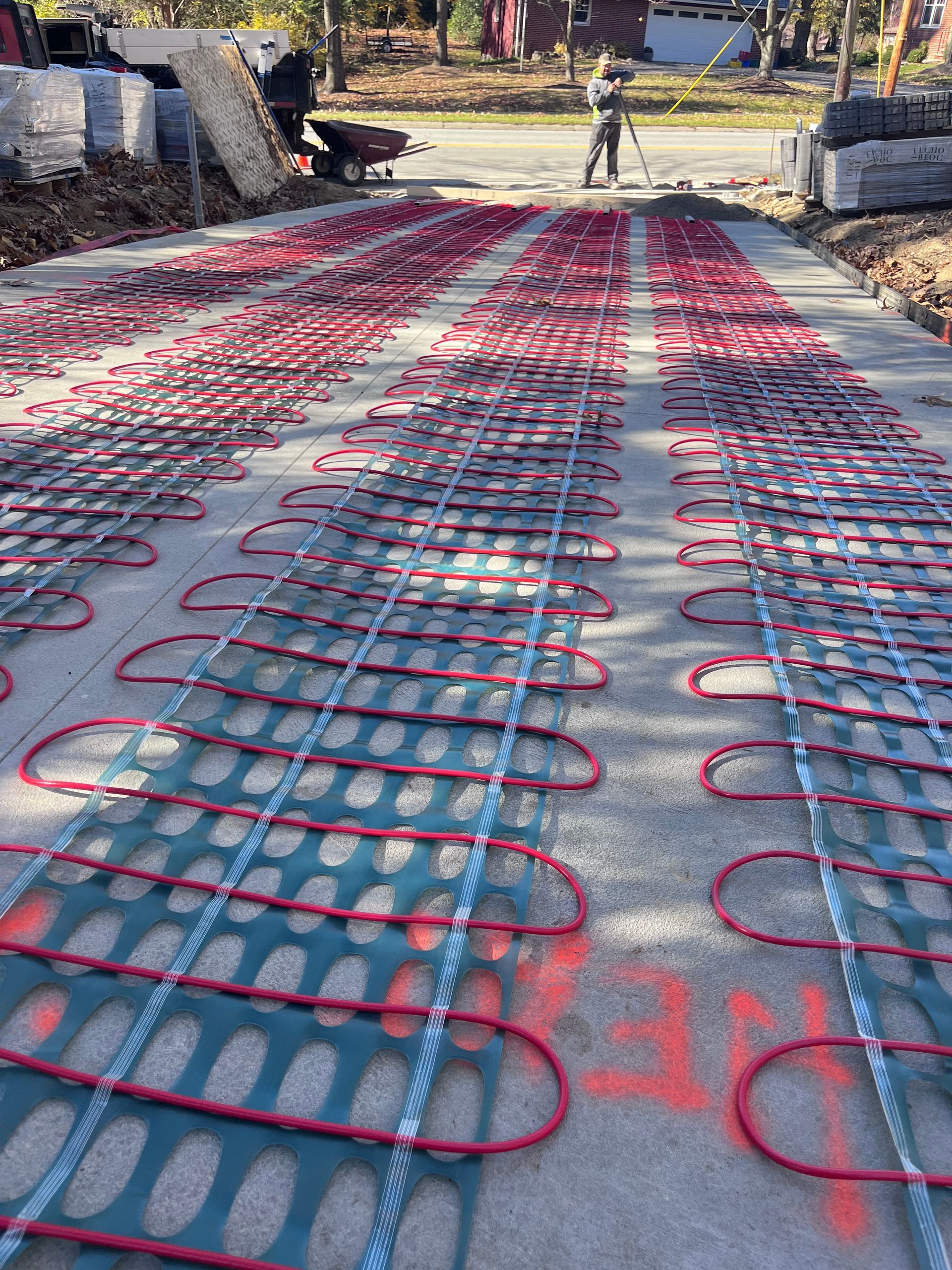 Red radiant heat tubes laid in a grid on concrete, awaiting a pour.