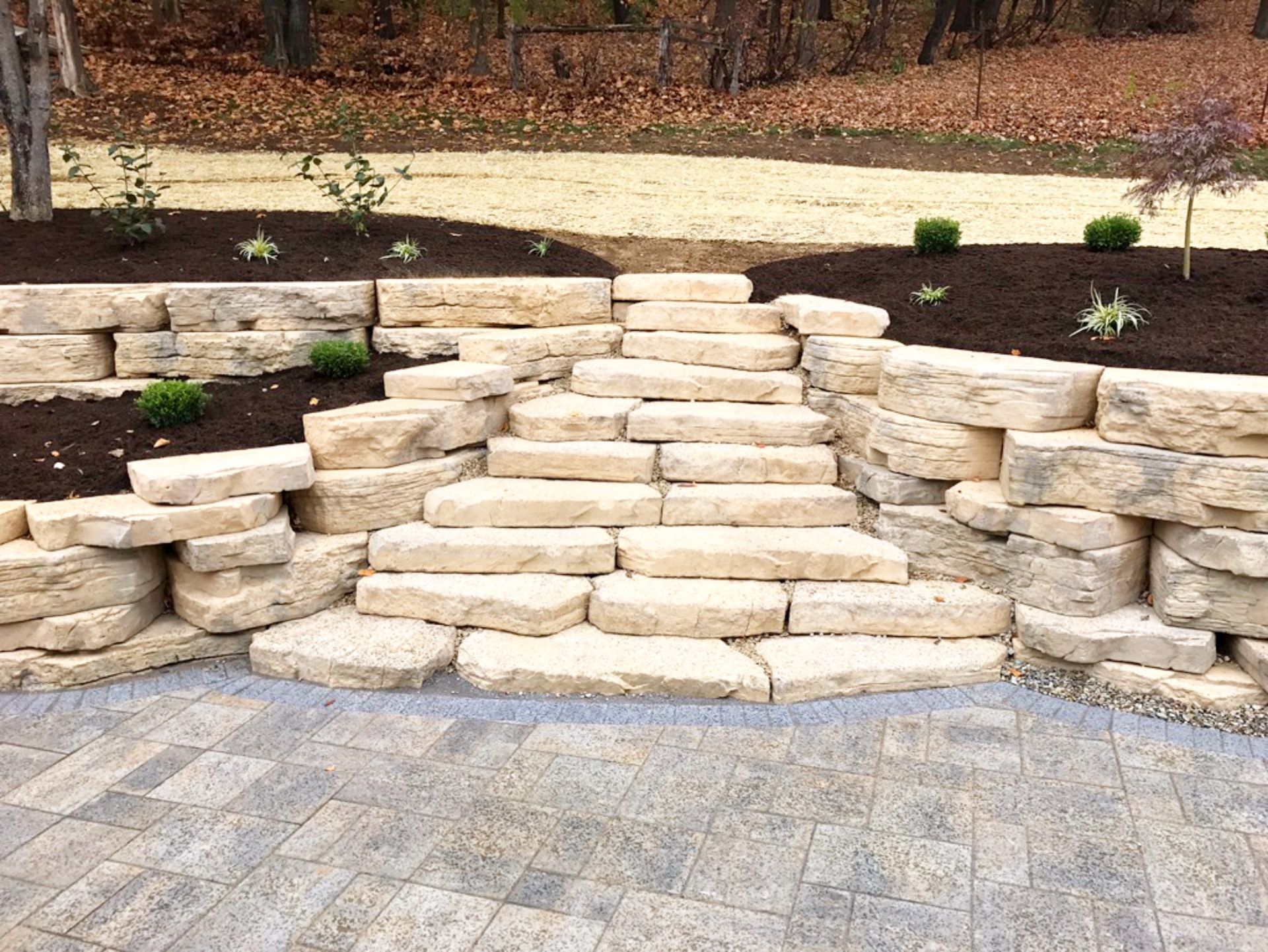 Stone steps built into a tiered retaining wall, leading to a mulch-covered garden area.