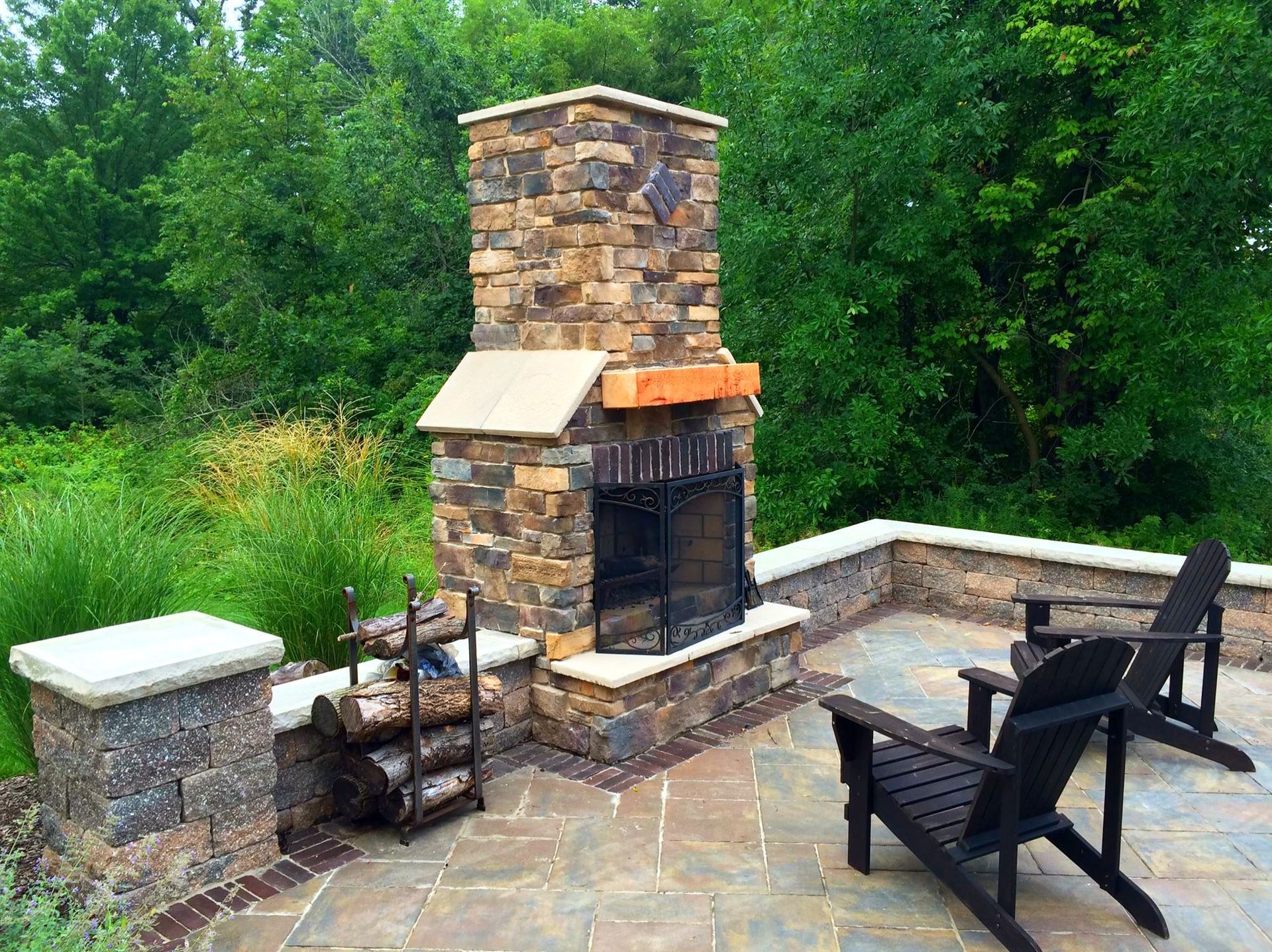 Outdoor stone fireplace with seating on patio.