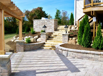 Stone steps leading up to a garden. Yellow and green plants on either side of steps.