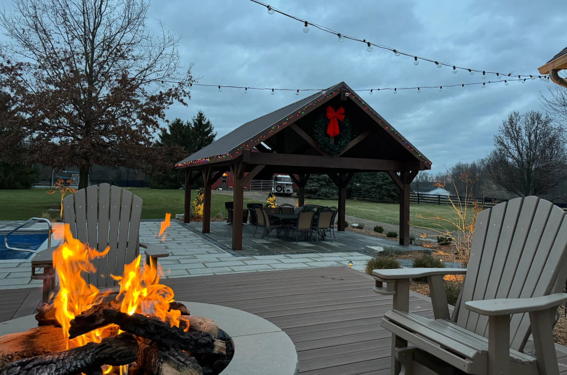 Wooden pergola over patio with dining table, overlooking a lake.
