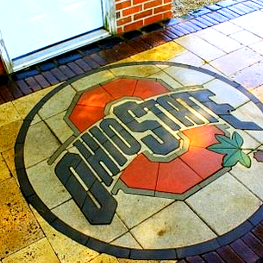 Ohio State logo inlaid in a brick patio near a door.