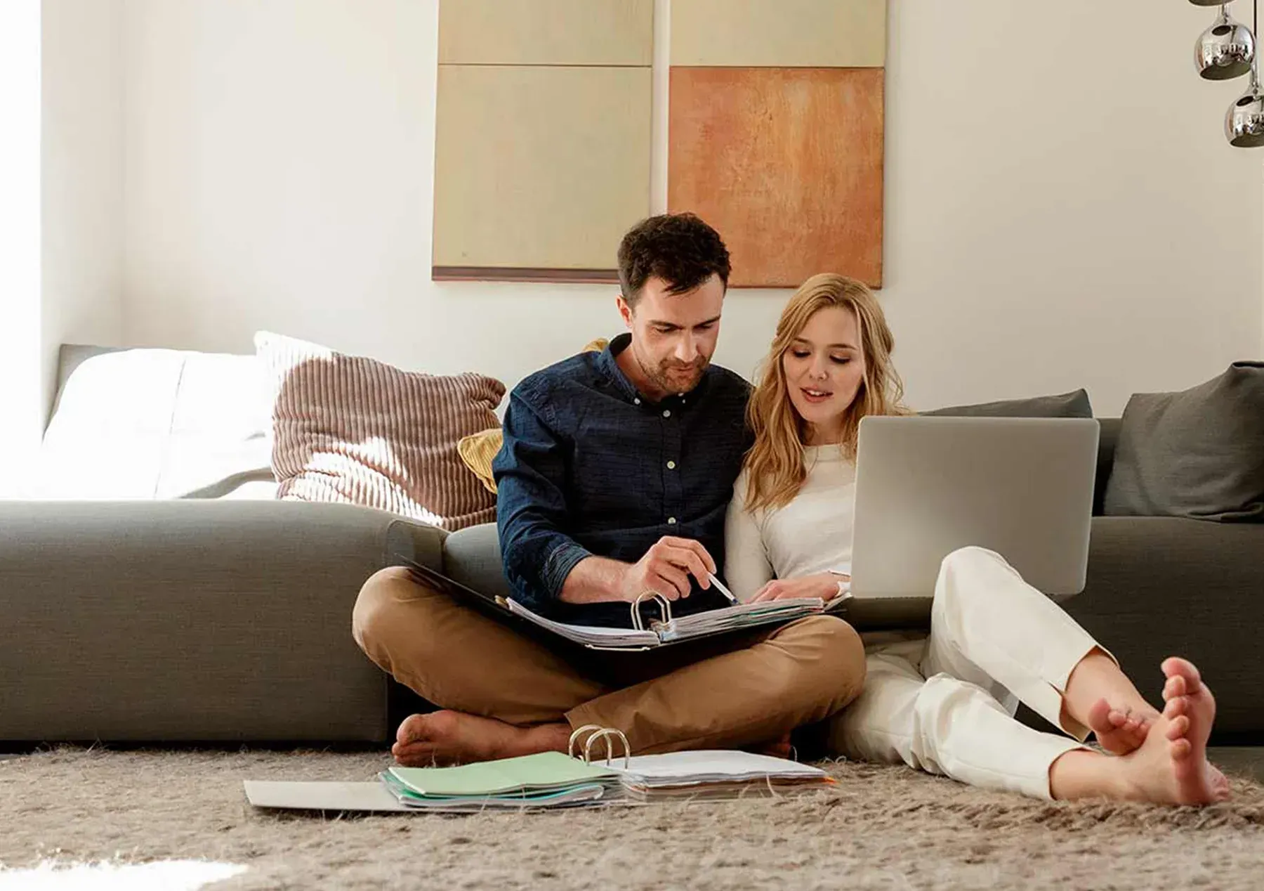 Two people sitting on the floor, working on a laptop in a cozy living room