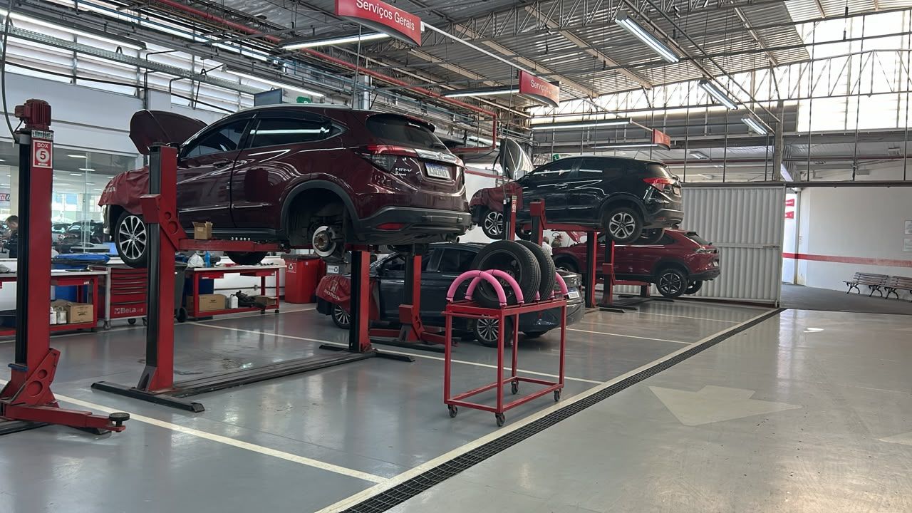 Car repair shop with two cars lifted on red hoists in a bright service bay