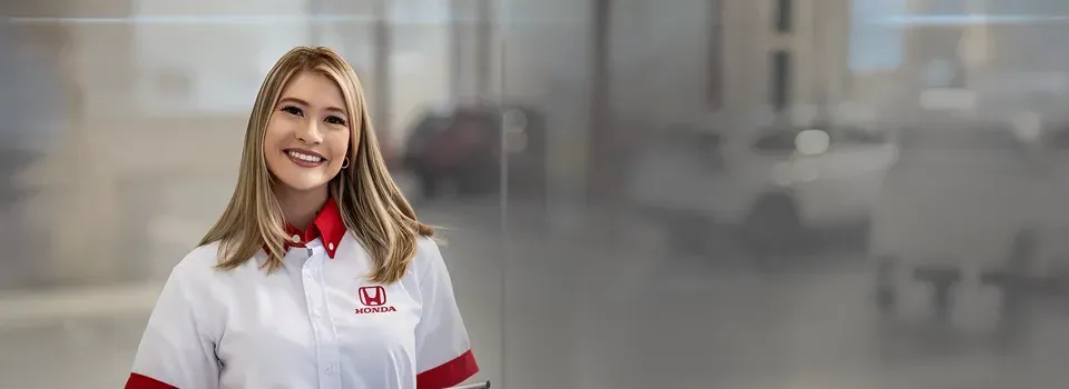 Smiling woman in a white shirt with red collar, standing against a blurred gray background.