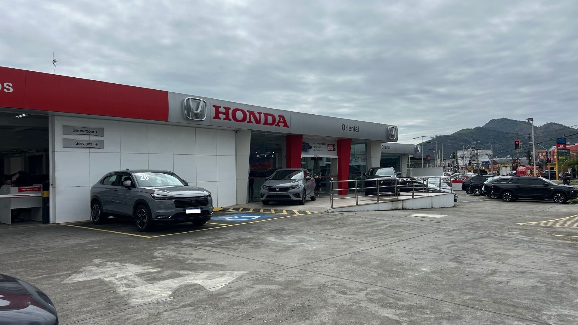 Honda dealership lot with cars parked outside under a cloudy sky