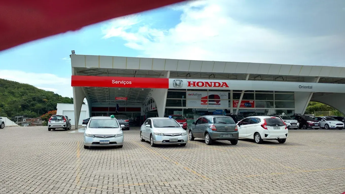 Concessionária Honda com vários carros estacionados sob uma cobertura que abriga o showroom.