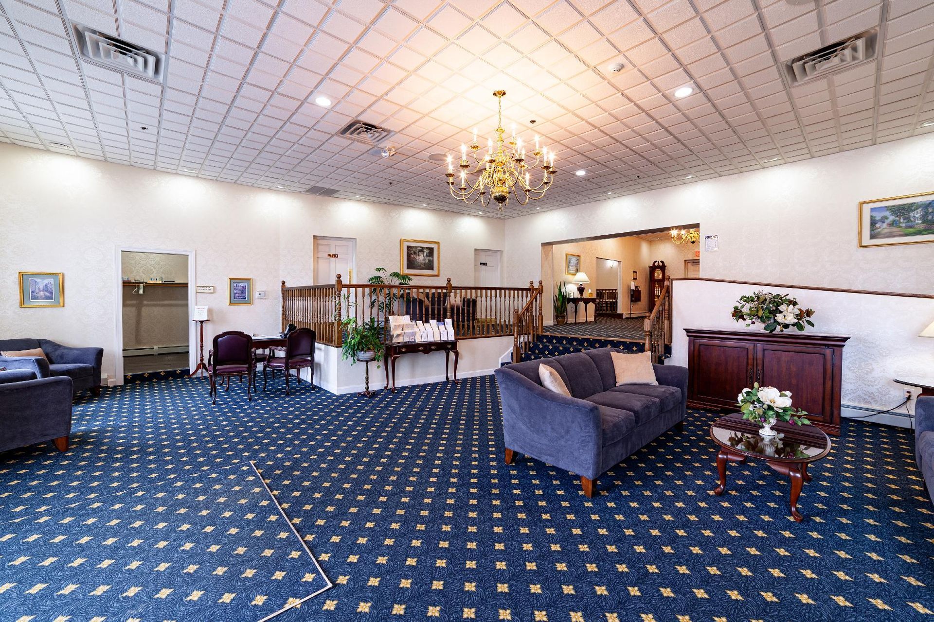 Hotel lobby with blue carpet, chandelier, seating area, and reception desk