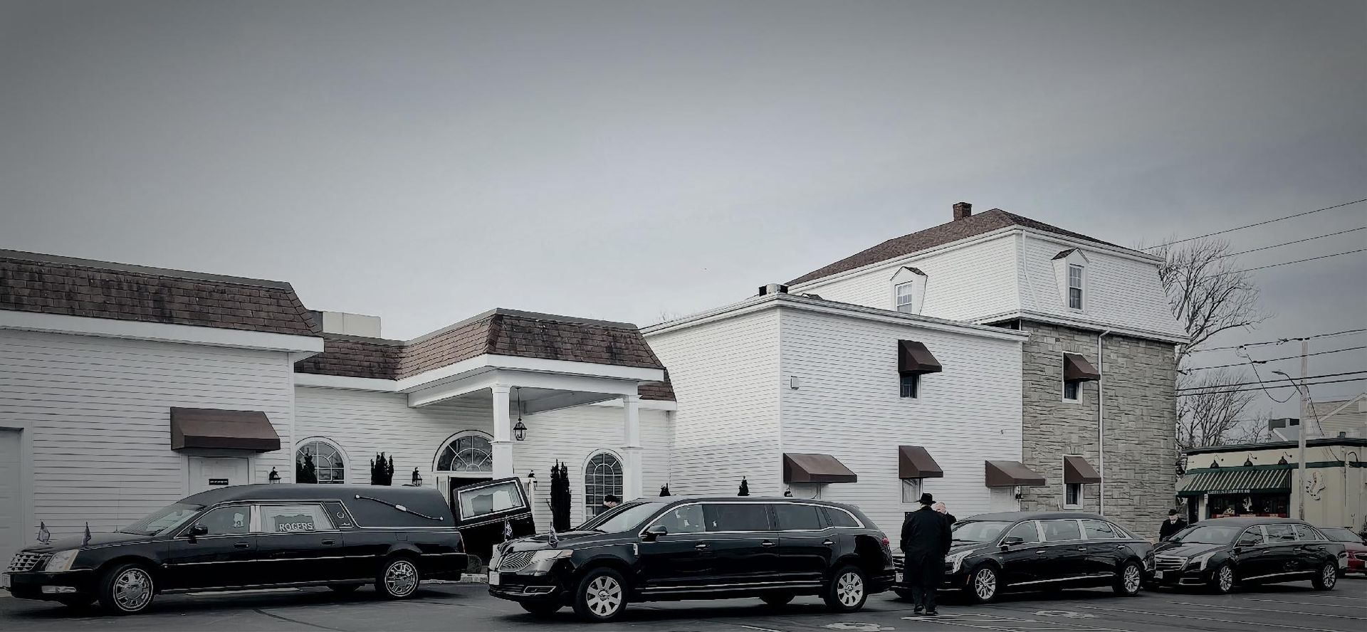 Snowy residential street with parked cars and a white two-story house