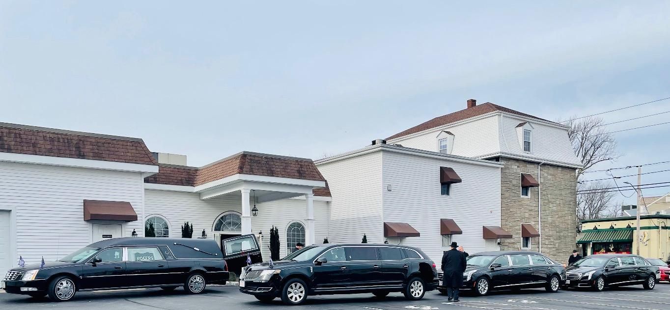 White stucco house with red-tiled roof and parked cars along the curb