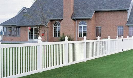 A brick house with a white fence in front of it.