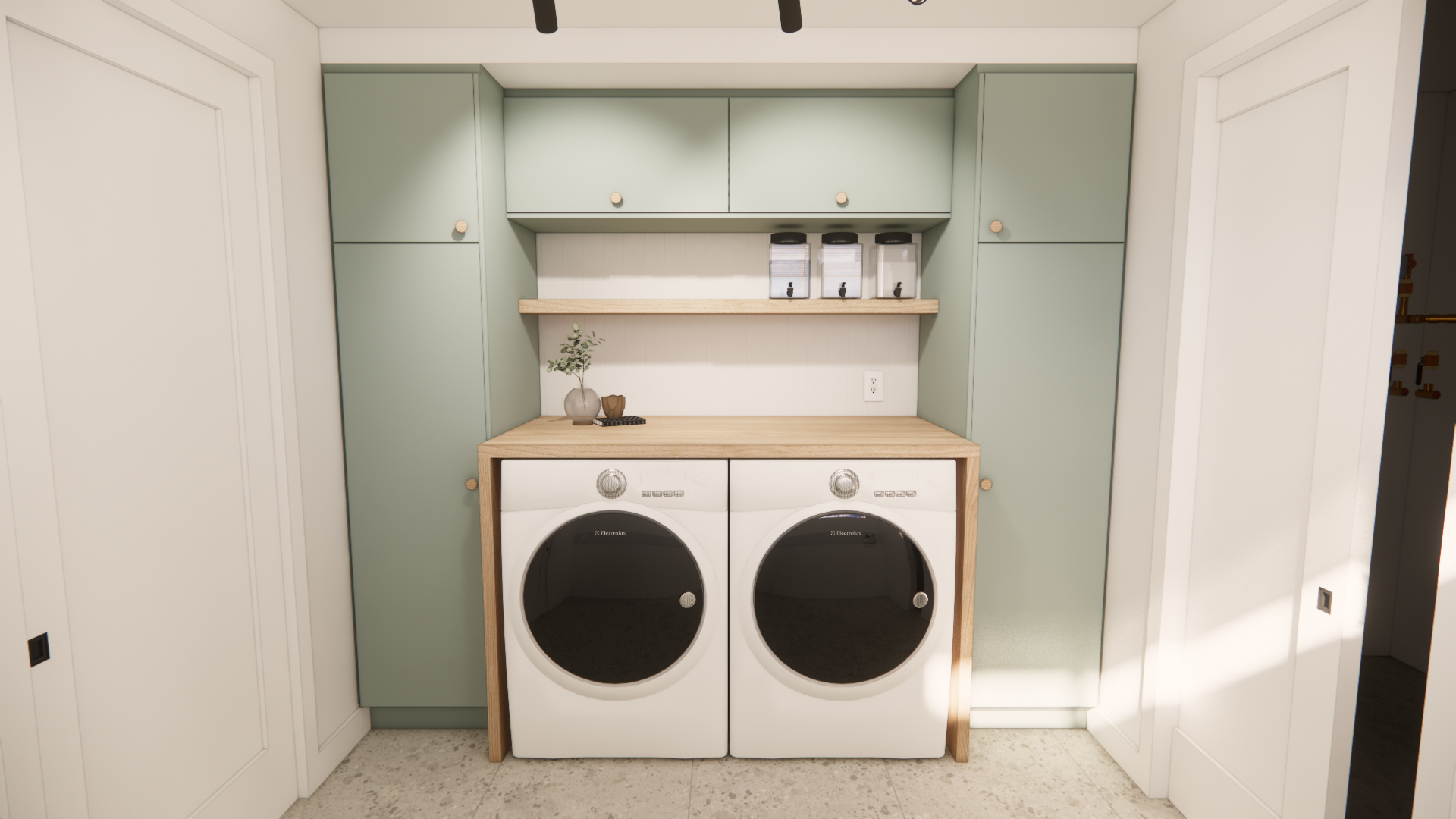 Buanderie avec placards vert sauge, plan de travail en bois clair et ensemble lave-linge/sèche-linge blanc.