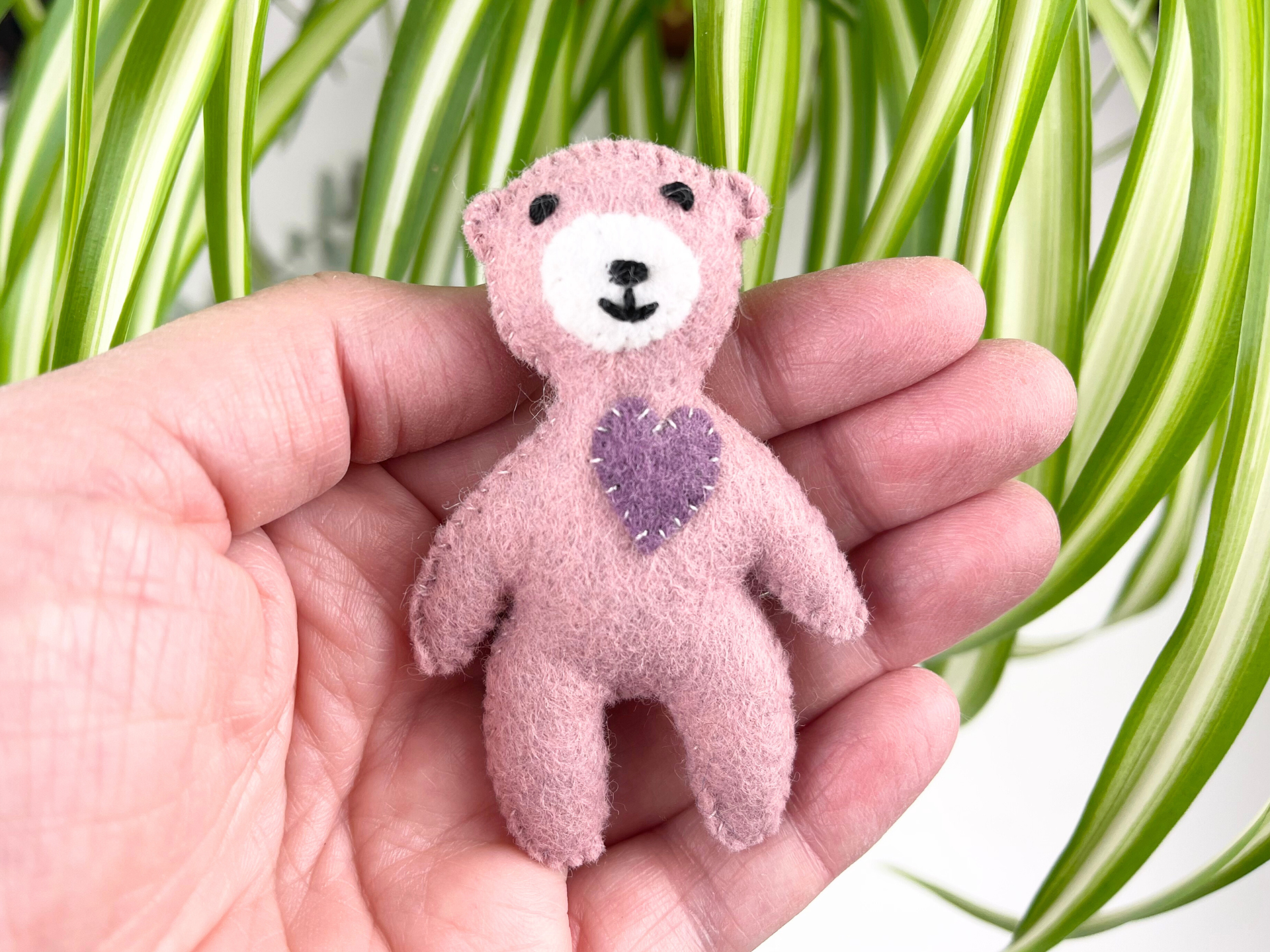 A mini felt bear, held in a hand, made from the free pattern offered by A Sewing Life