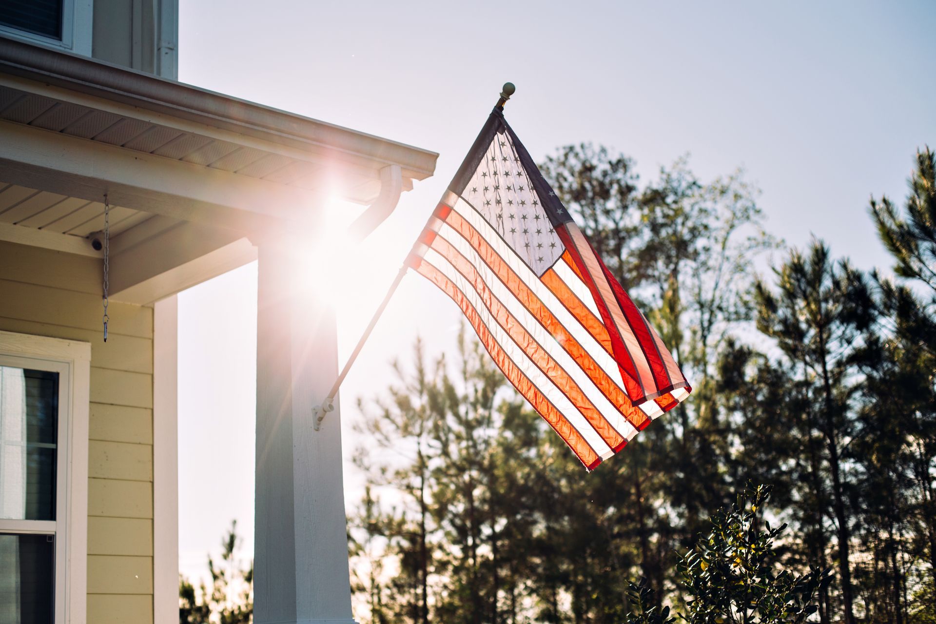 American flag waving on a flagpole against a partly cloudy blue sky.