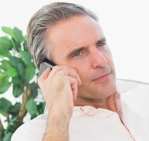 A man in a blue t-shirt is smiling and looking up