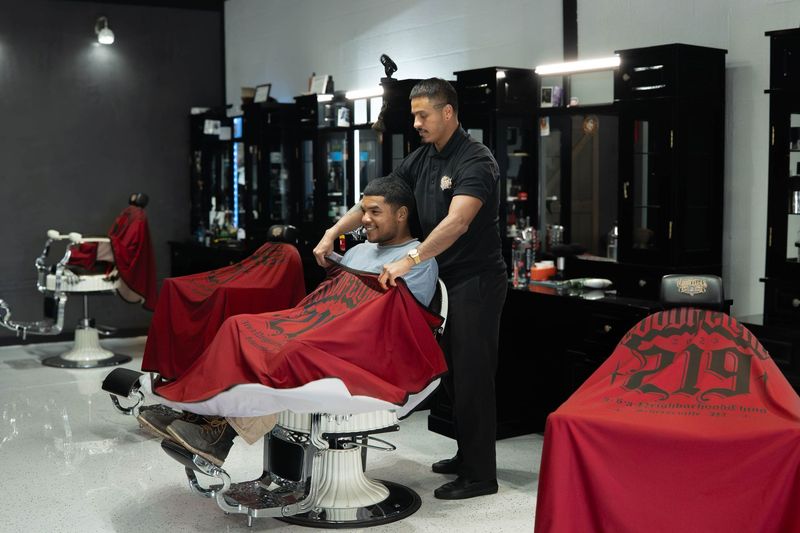 Barber snapping a cape on a client before a fade haircut at Goodfellas Barbershop