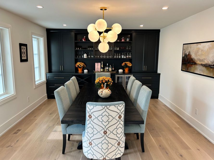 Elegant dining room with long dark table, black cabinets, and gold globe chandelier.