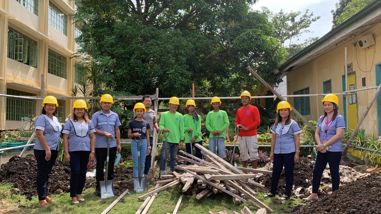 A group of people wearing hard hats are standing in front of a building.