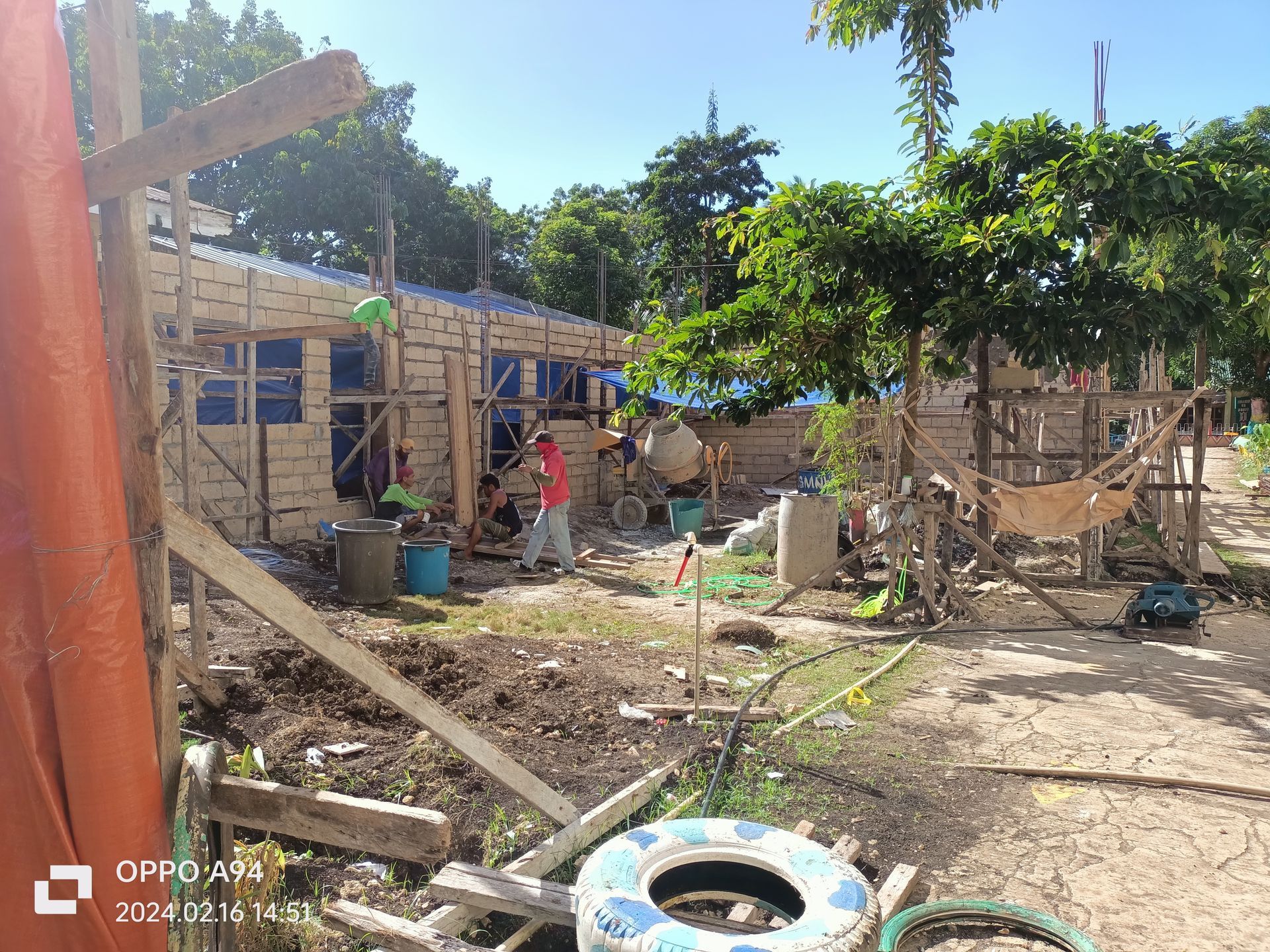 A group of people are working on a building in a field.